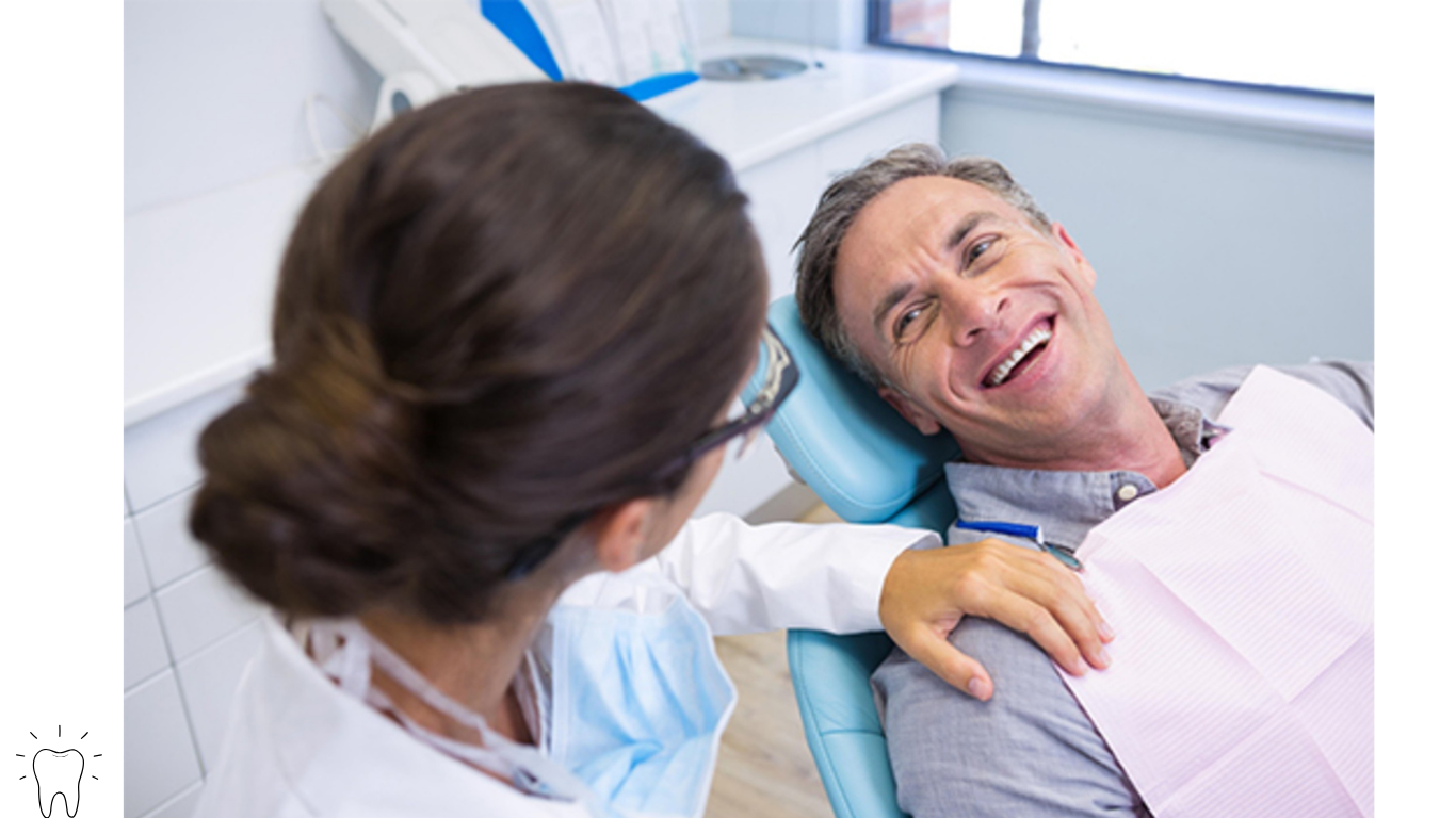 A man lying in a dental chair smiling and talking with a female dentist.