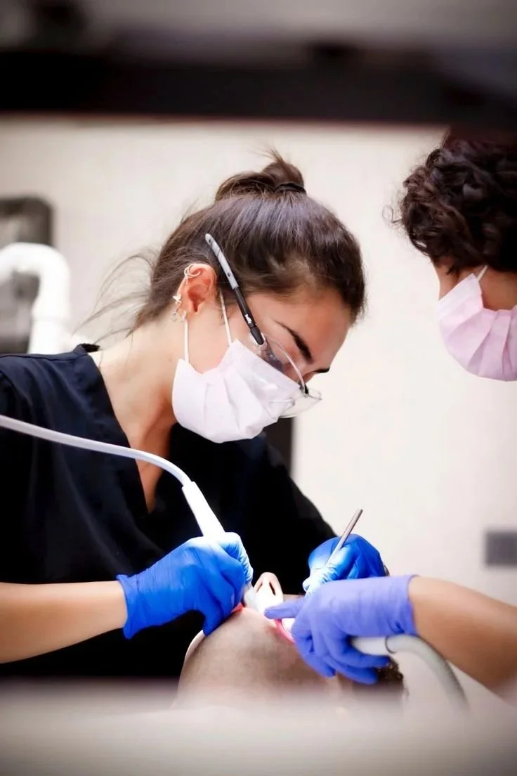 Dental professionals performing a dental procedure on a patient in a clinical setting.