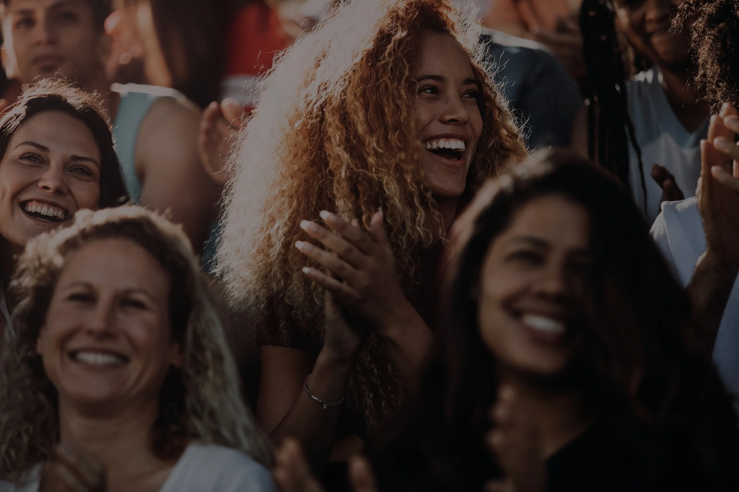 Group of people smiling and enjoying an outdoor event during the daytime.