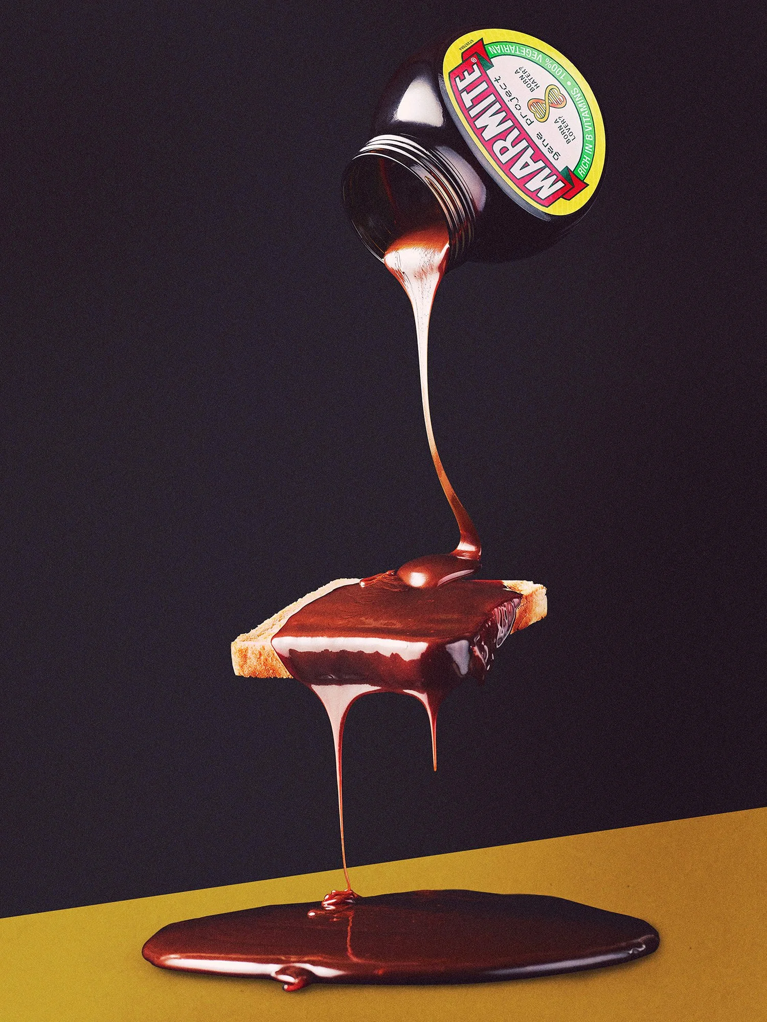 Marakalite chocolate syrup being poured from a jar onto a slice of bread, with some syrup dripping down.