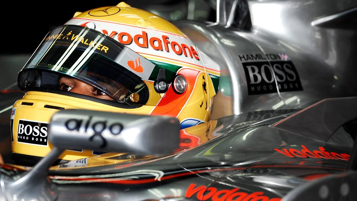 Close-up of Lewis Hamilton seated inside his Formula One car, helmet on, moments before racing