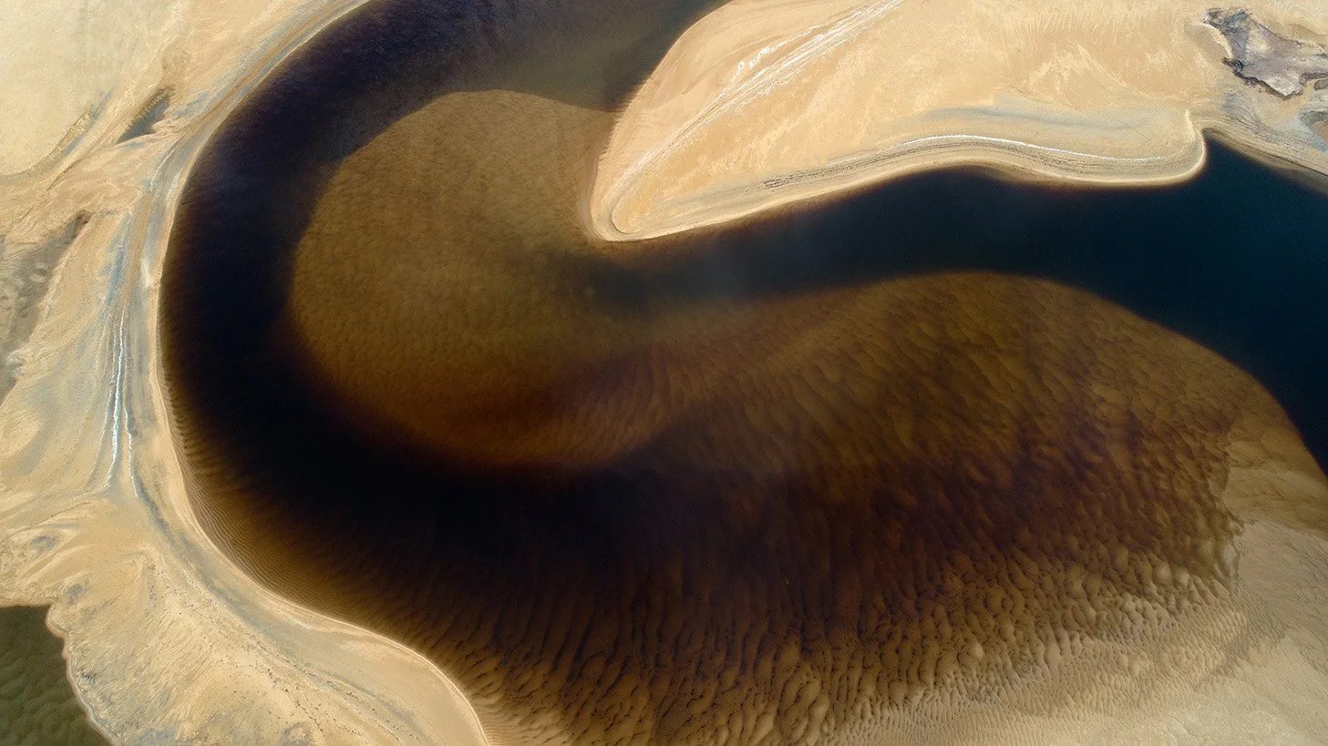 Aerial photograph of a hairpin river bend at Gong Balai, showing dark brown and blue water flowing through surrounding land.