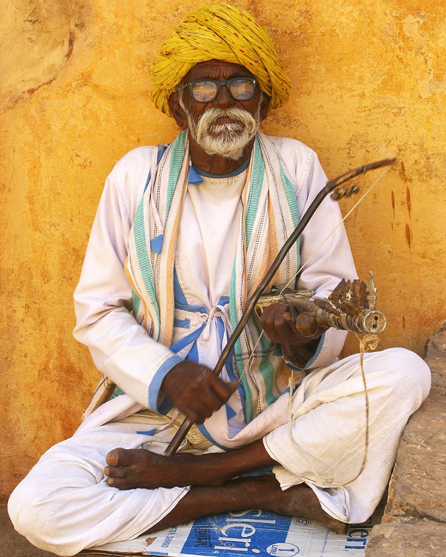 Street musician photographed in New Delhi, looking directly toward the camera.