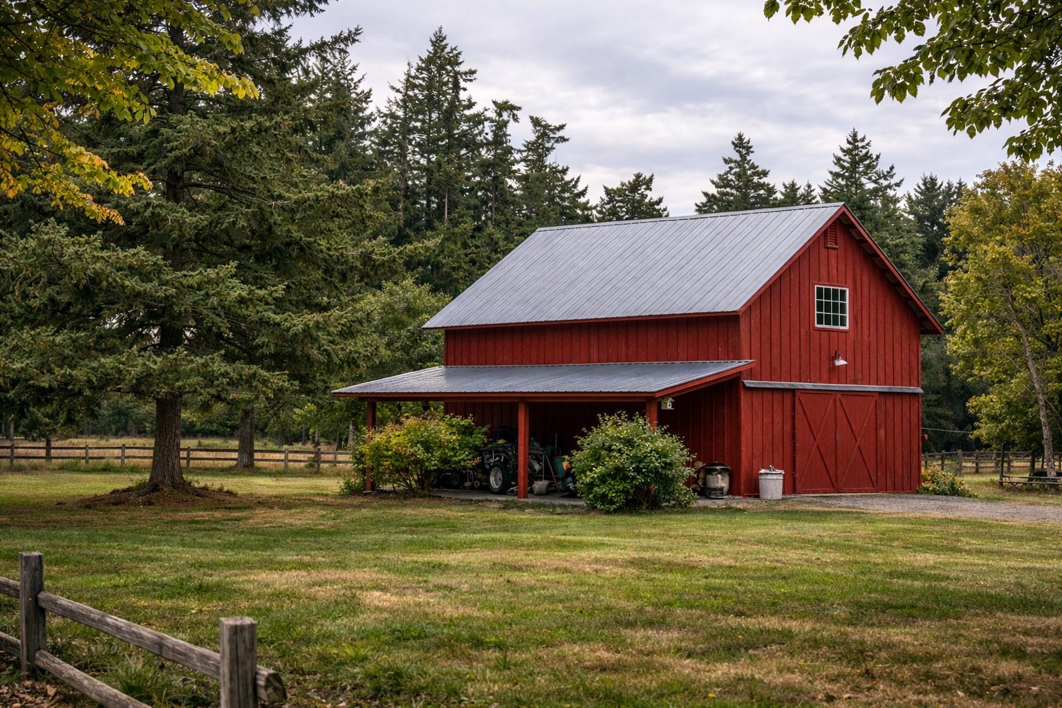 Red barn on a grassy field with trees in the background.  Post Frame Barn built in Burlington