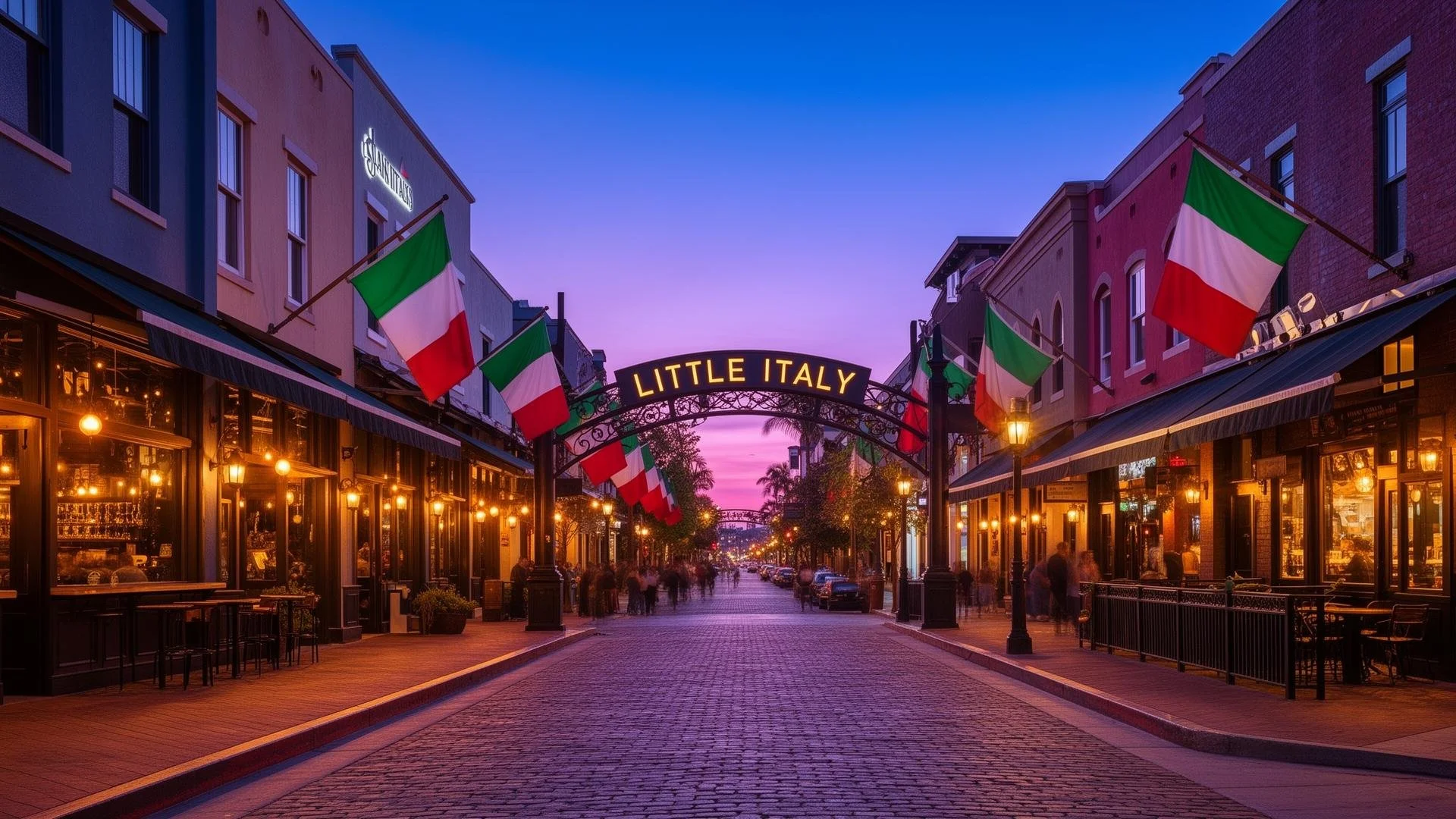 A pedestrian street called Little Italy at sunset, with Italian flags hanging on both sides, street lamps lit, and people walking along the sidewalk.