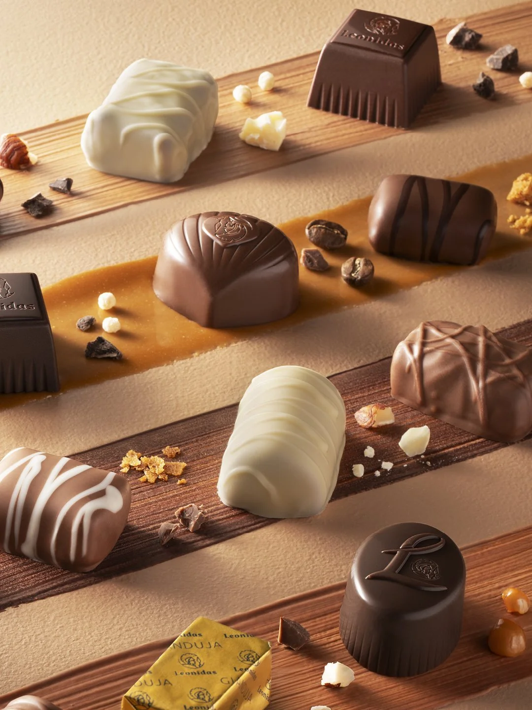 Assorted chocolates and confections displayed on wooden boards with scattered small chocolate pieces and nuts.