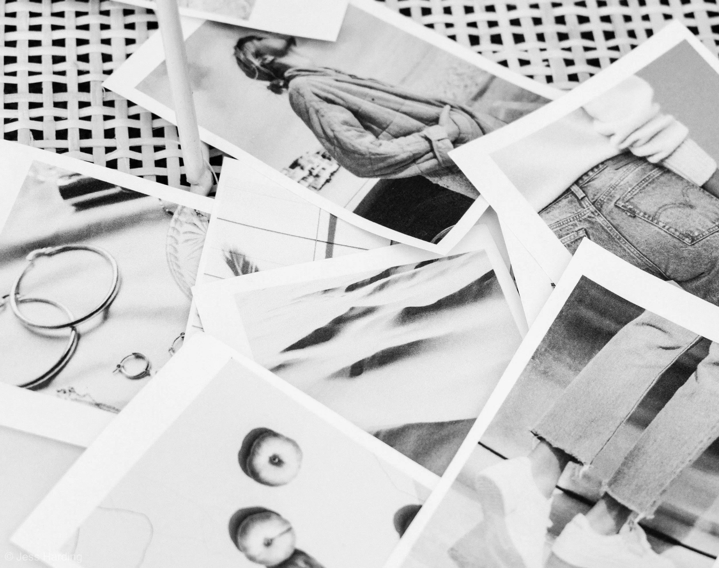 A collection of scattered black and white photographs of various objects, including a person wearing a coat and jeans, a pair of earrings, and a fruit.