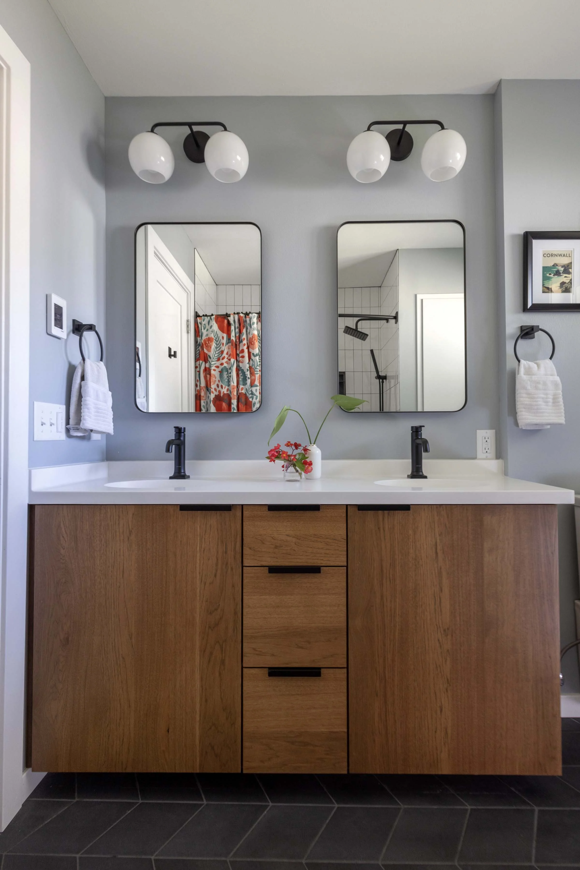 Symmetrical primary bathroom vanity installation with dual mirrors, black hardware, and custom wood cabinetry.