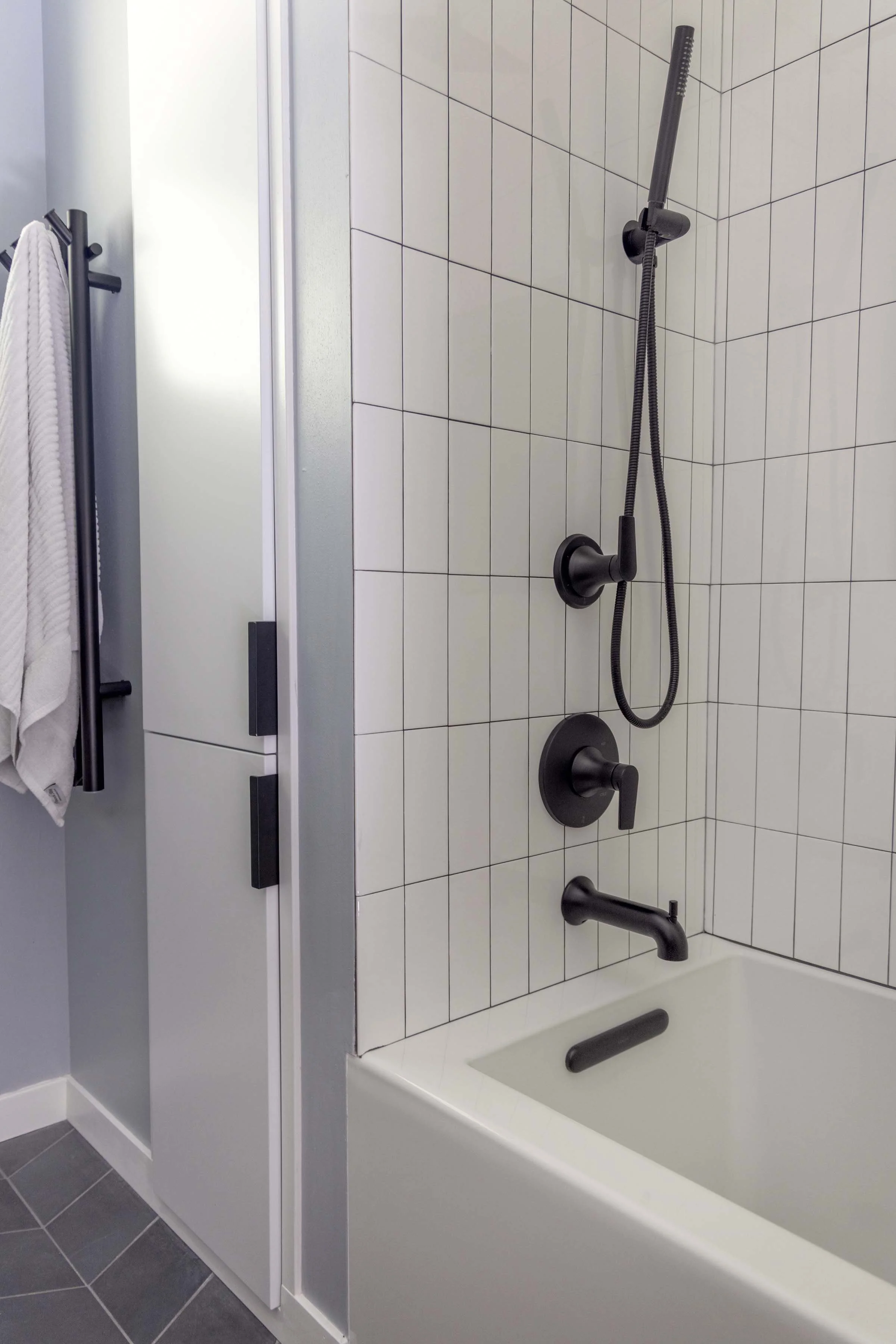 Complete custom tub and shower remodel by Root Down Remodeling featuring matte black plumbing fixtures and glass doors.