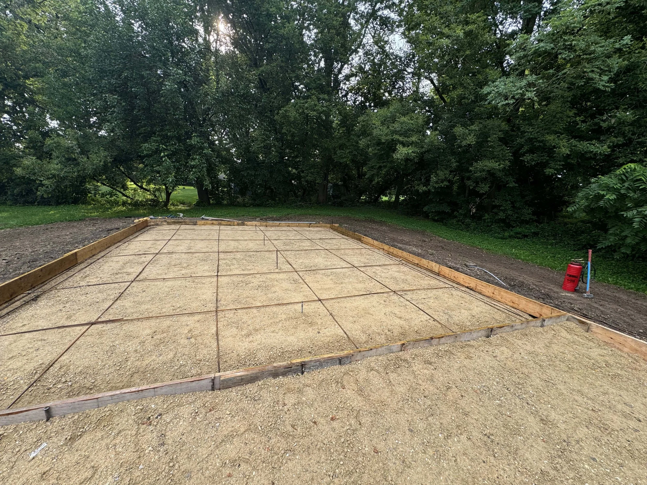 Prepared gravel foundation base grid ready for a custom garage concrete pour.