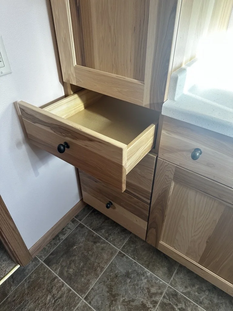 Open pull-out storage drawer inside a wood linen cabinet.