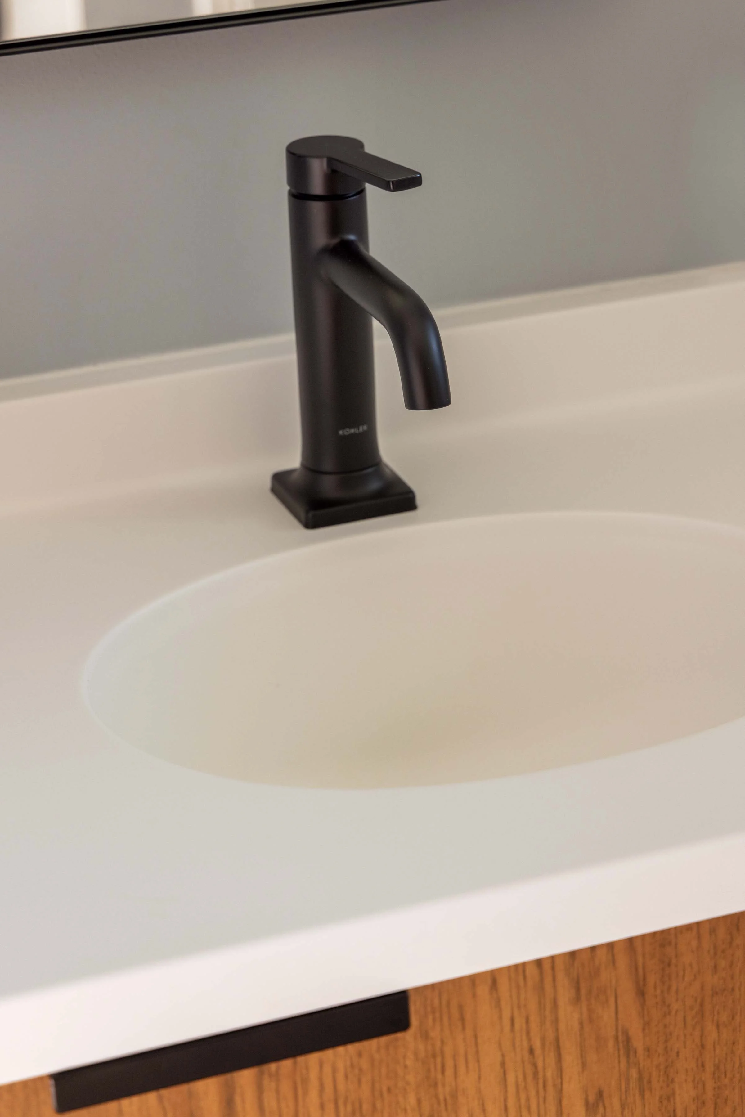 Matte black gooseneck bathroom faucet installed on a seamless white undermount sink.