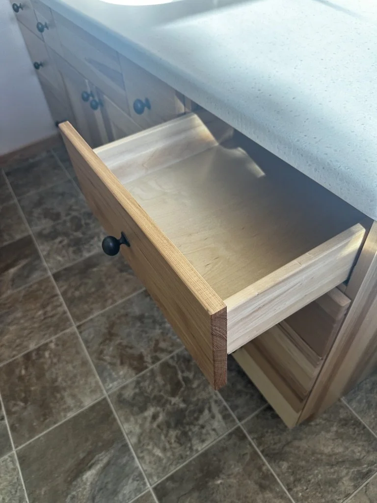 Open wooden vanity drawer showcasing internal bathroom storage.