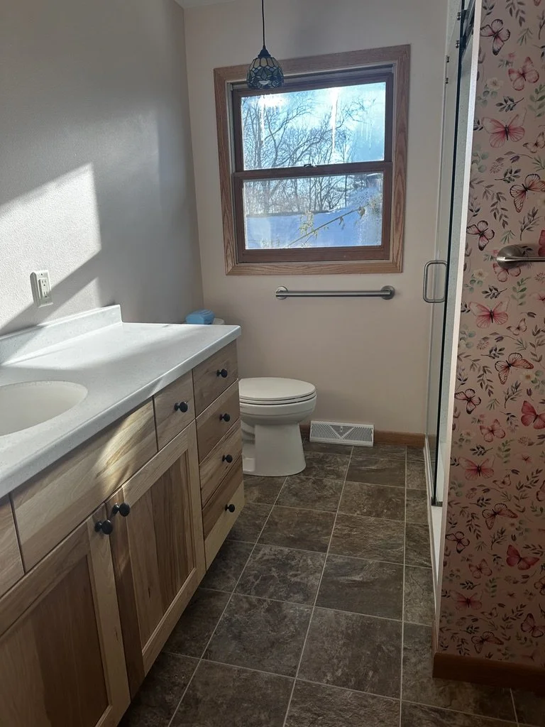 Long layout view of a bright bathroom featuring solid surface countertops.