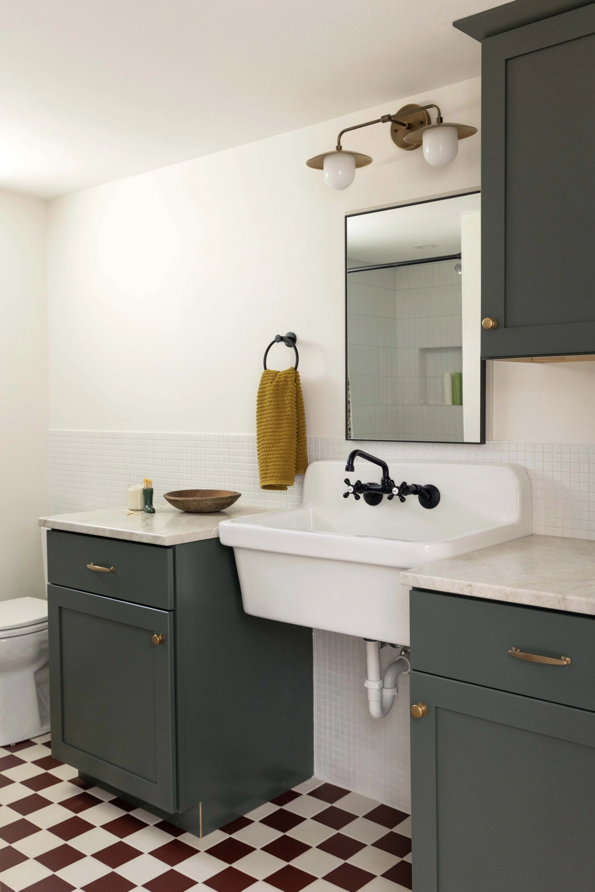 Finished basement bathroom remodel by Root Down Remodeling featuring custom painted green cabinetry.