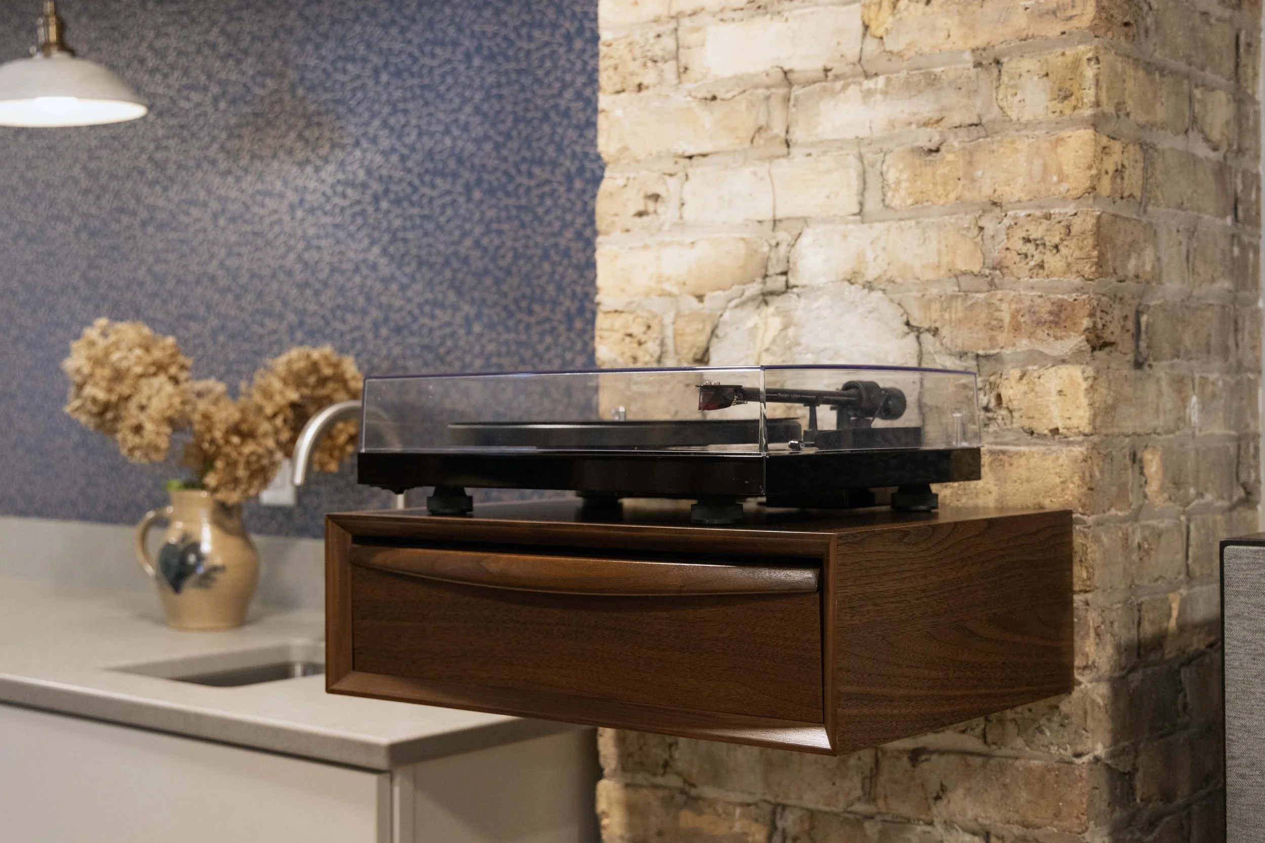 Custom floating wood shelf built by Root Down Remodeling to house a turntable setup.