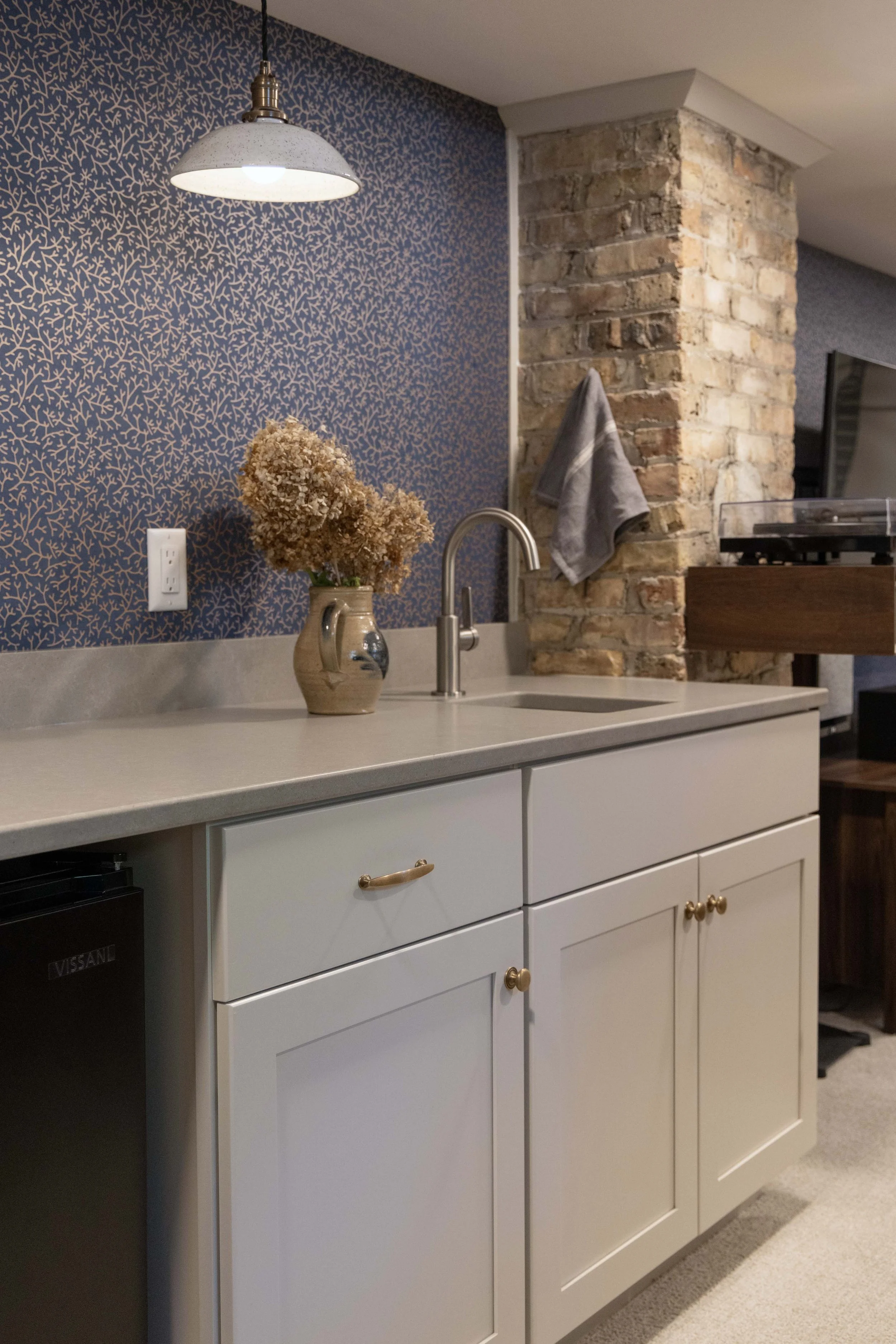 Custom basement wet bar installation featuring seamless quartz countertops and an integrated under-counter fridge layout.