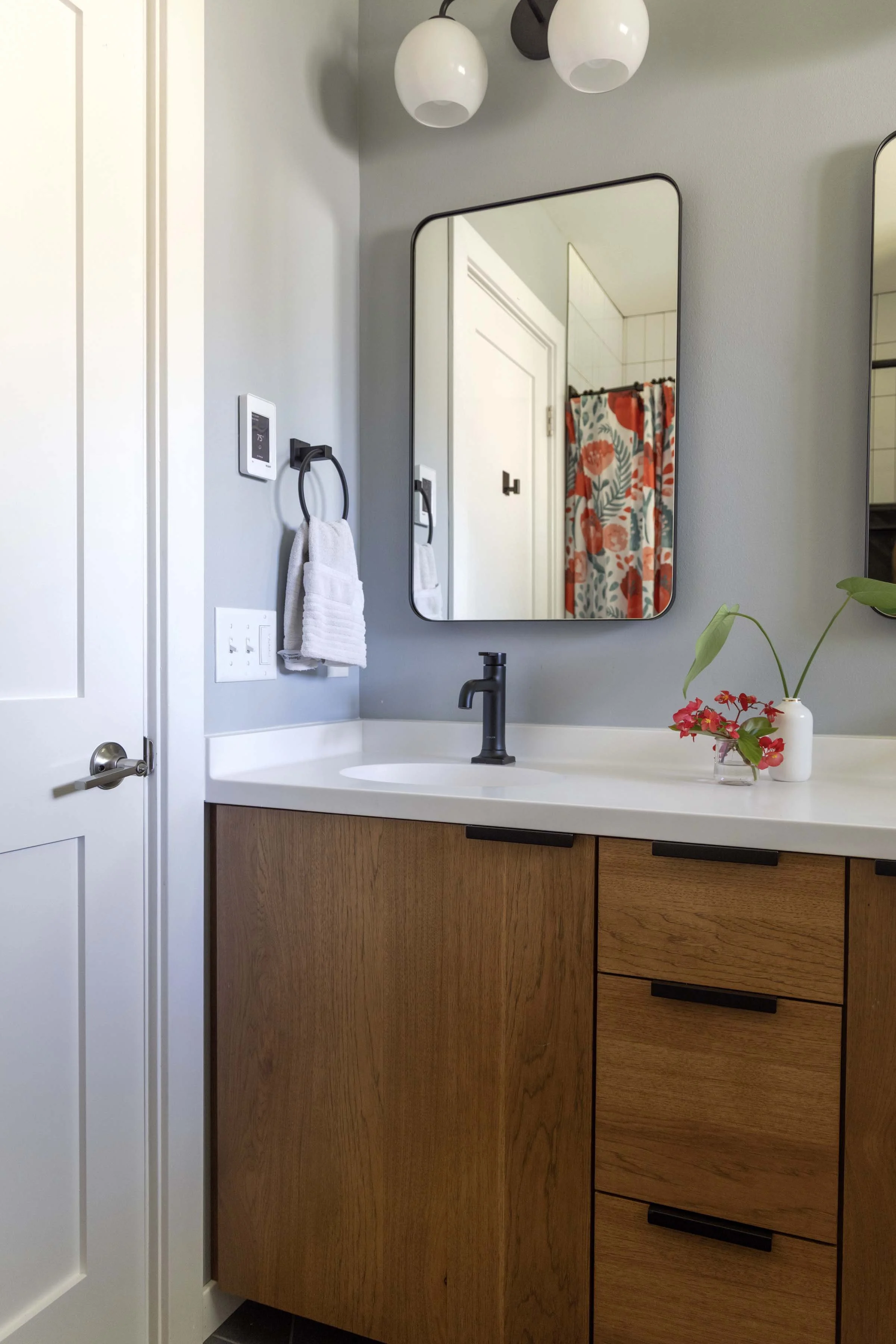 Single-sink view of a custom wood double vanity styled with minimalist floral accents.