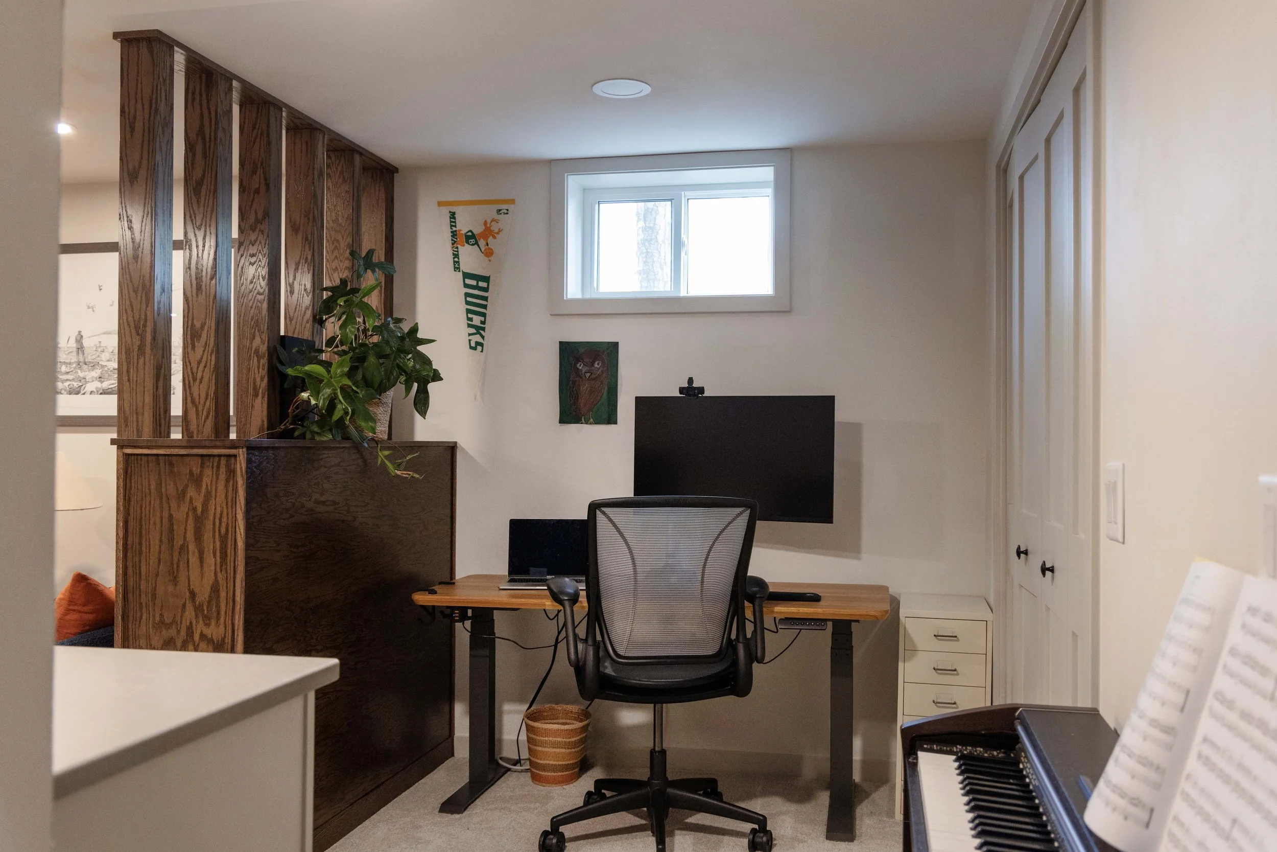 Finished basement workstation setup with a computer monitor beneath a small egress window.