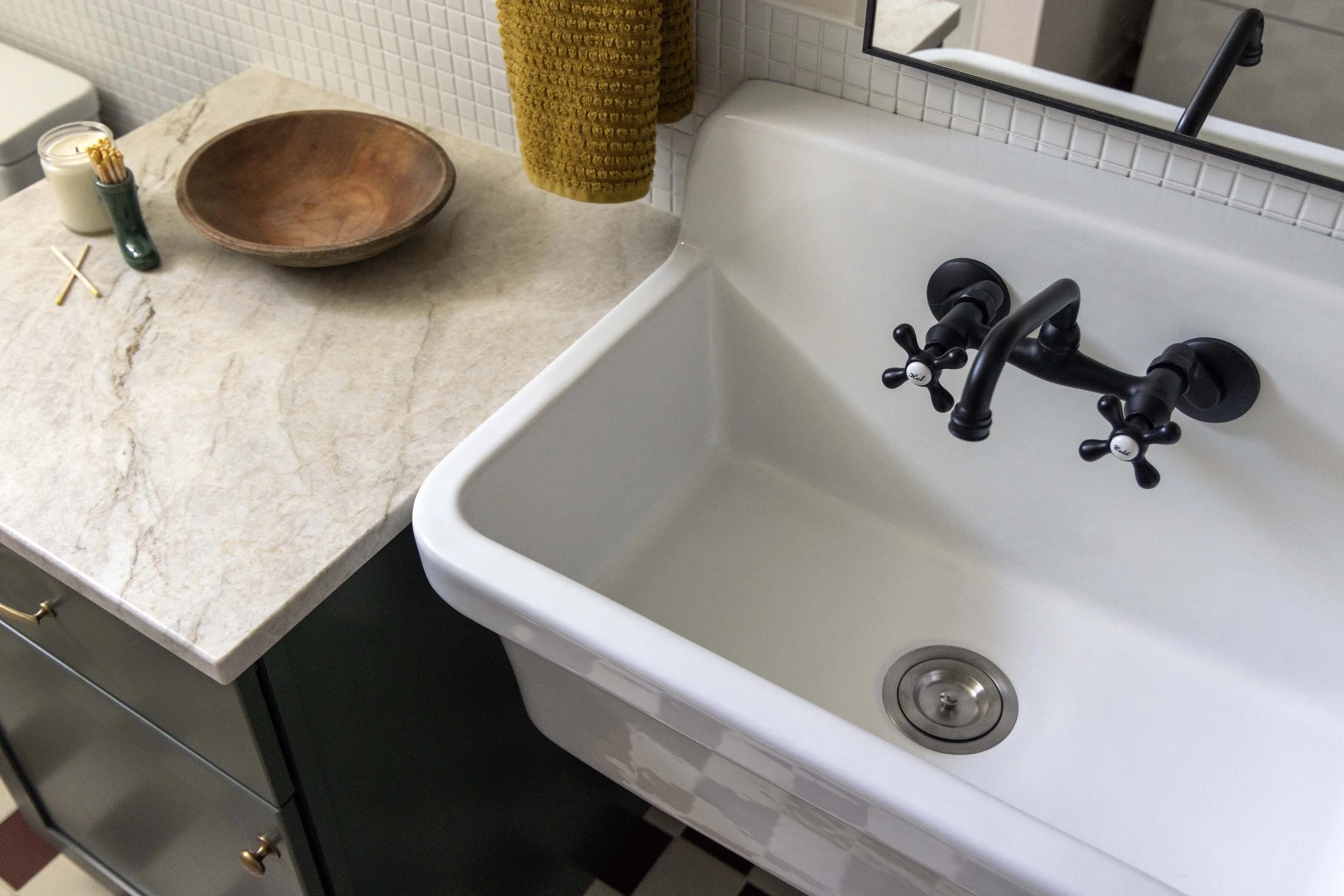 High-end basement bathroom featuring a white farmhouse utility sink with a black wall-mounted faucet.