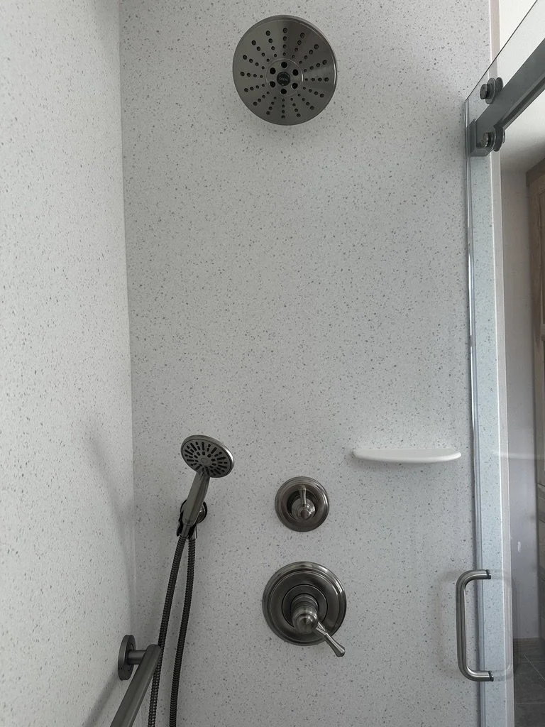 Corian solid surface shower surround panels paired with premium chrome plumbing hardware.