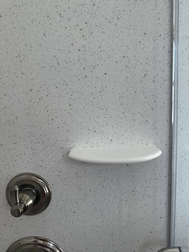 Built-in solid surface corner shaving footrest or soap shelf installation details.