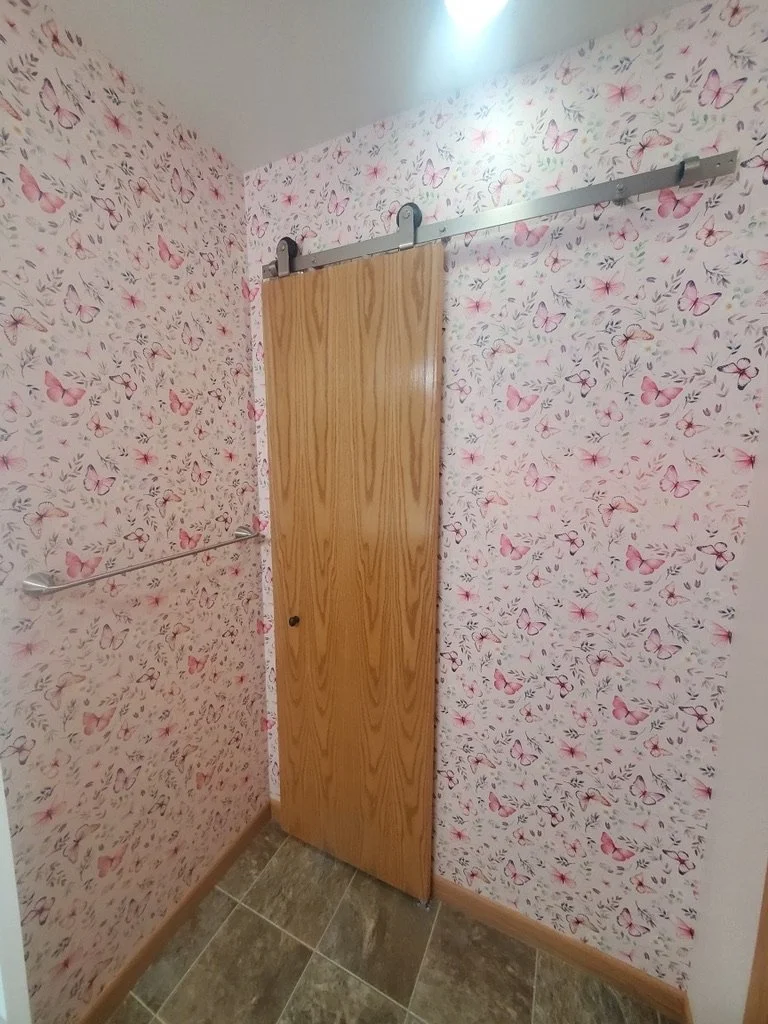 Space-saving wood barn door configuration in a bathroom remodel.