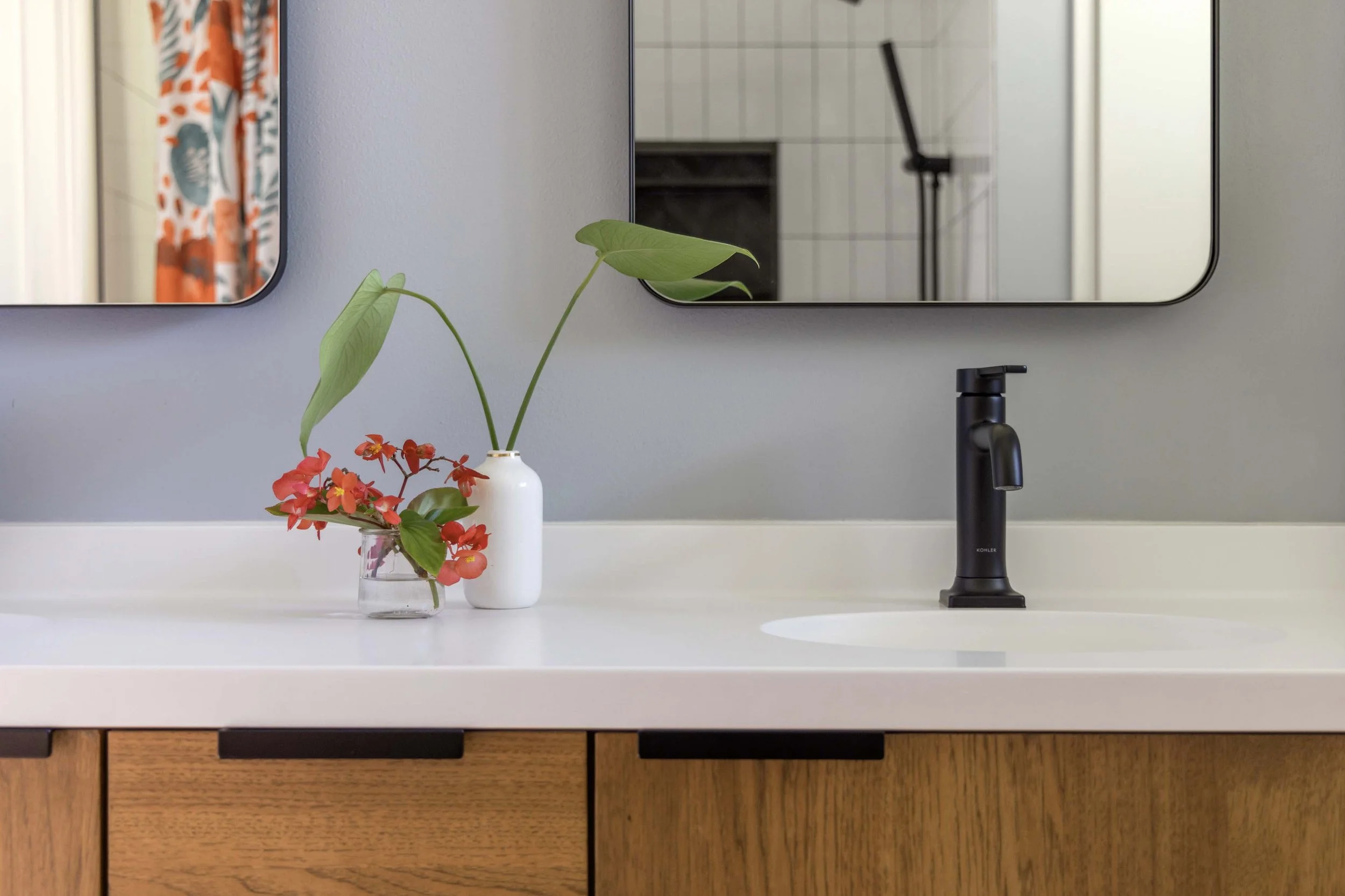 Close-up detail of smooth white bathroom countertops, integrated sink, and an oil-rubbed black faucet.