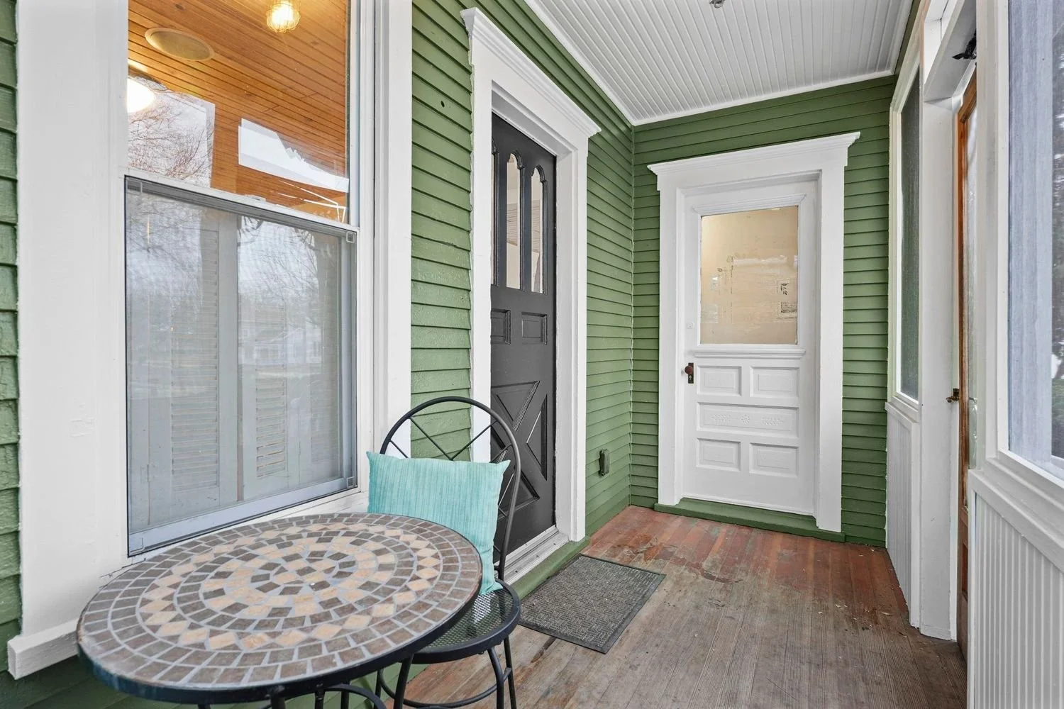 Historic Victorian exterior porch remodel by Root Down Remodeling featuring green siding and classic white trim.
