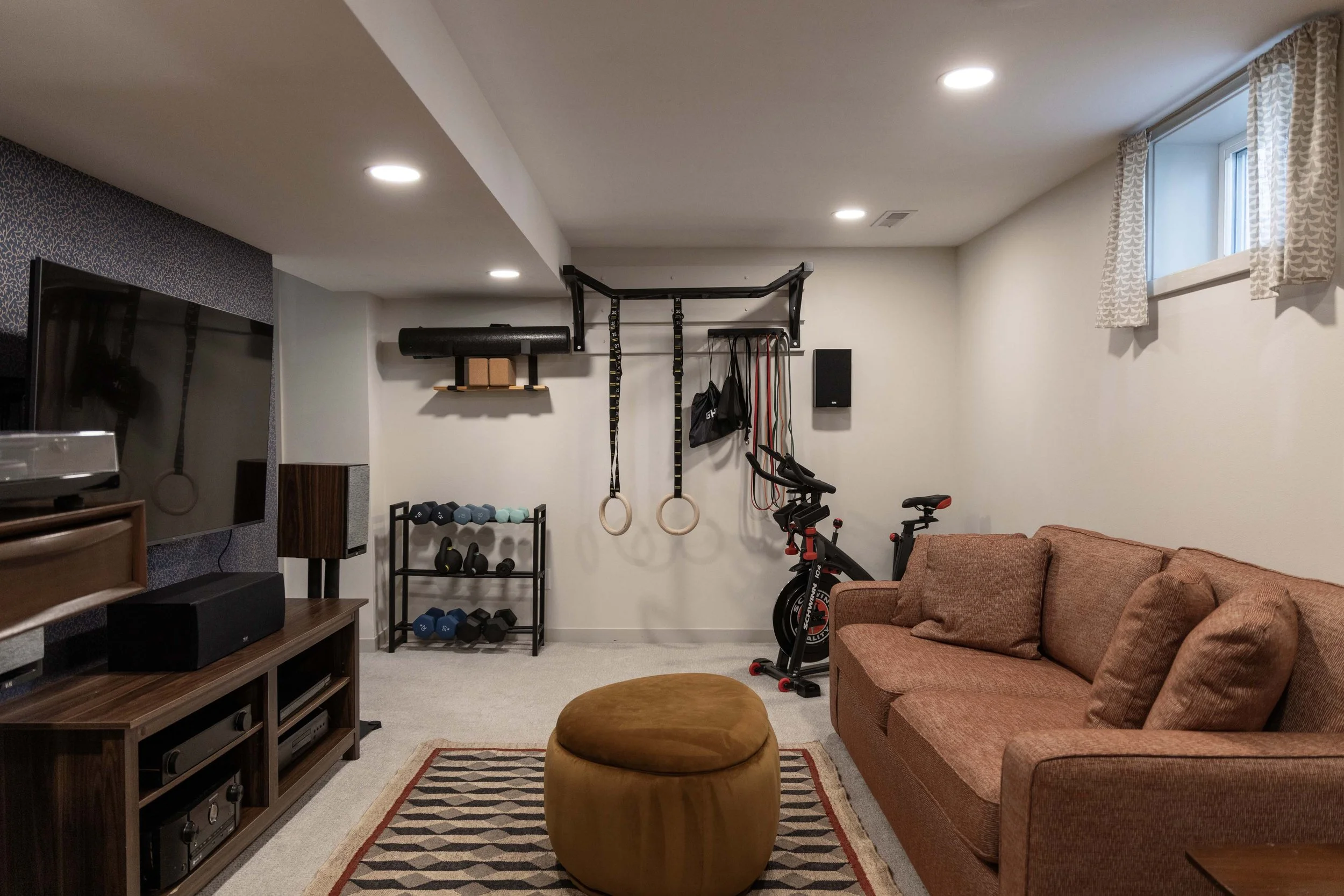 Multi-functional finished basement layout combining a media lounge area with an integrated home gym space.