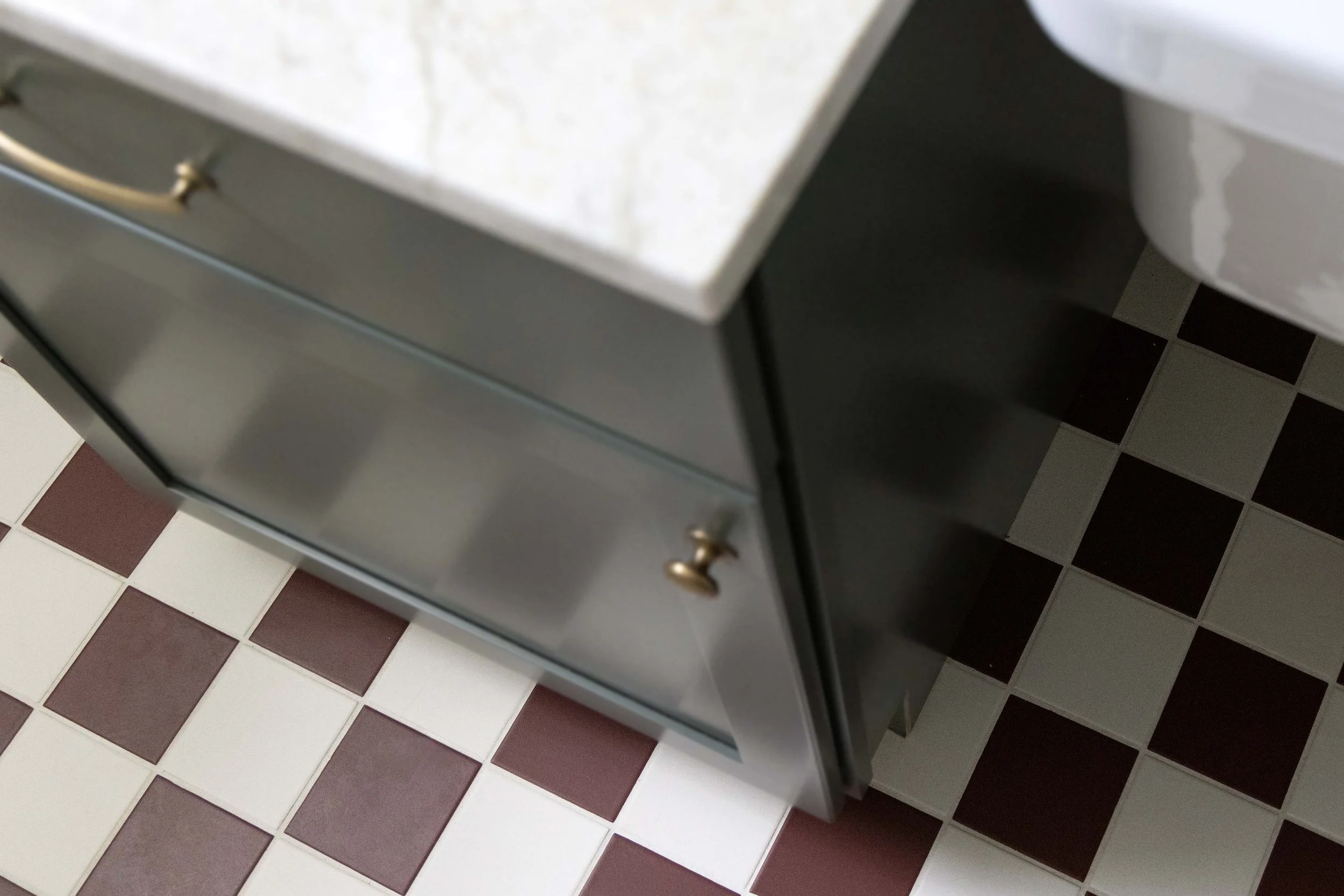 Profile view of a custom bathroom vanity showing a quartz top, gold hardware, and dark green painted finish.