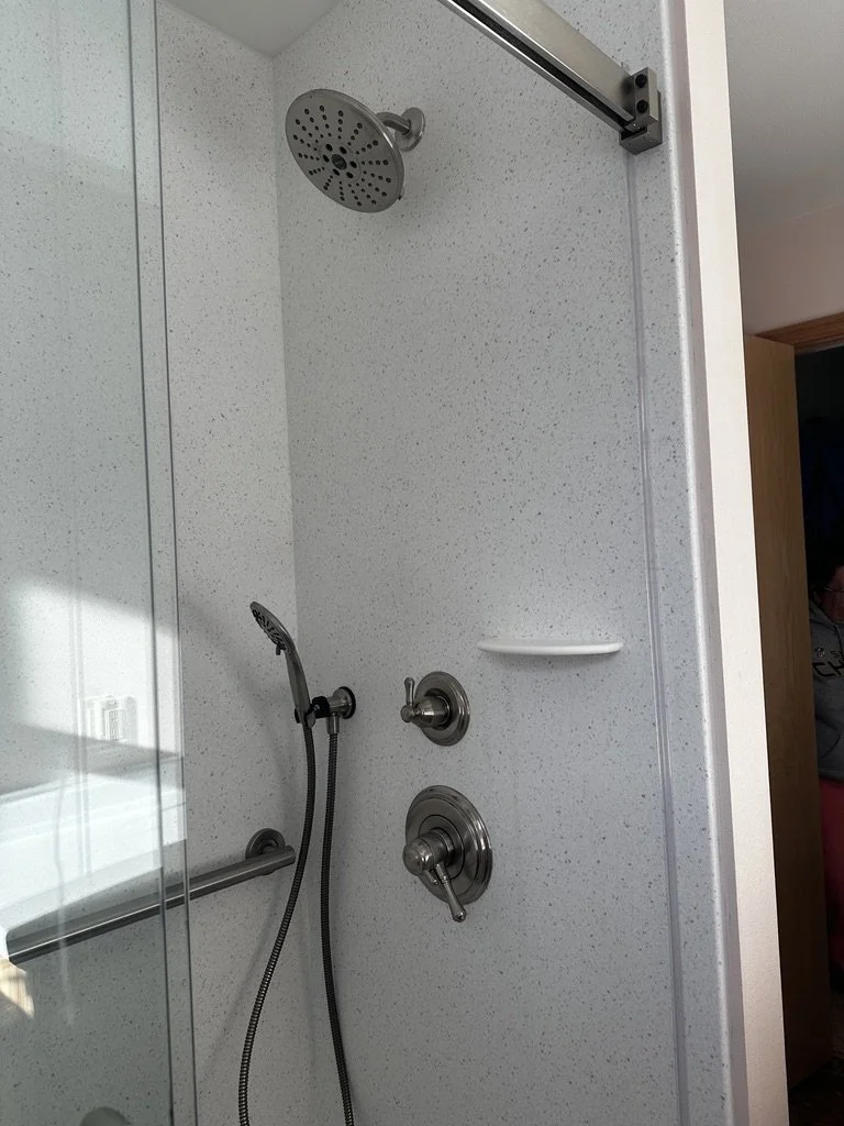 Custom walk-in shower built by Root Down Remodeling featuring Corian Ice Queen walls.