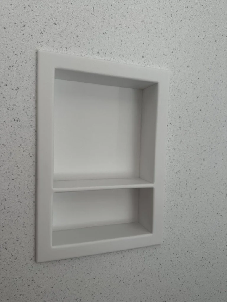 Close-up detail of a custom-fabricated Corian recessed shower shelf by Root Down Remodeling.