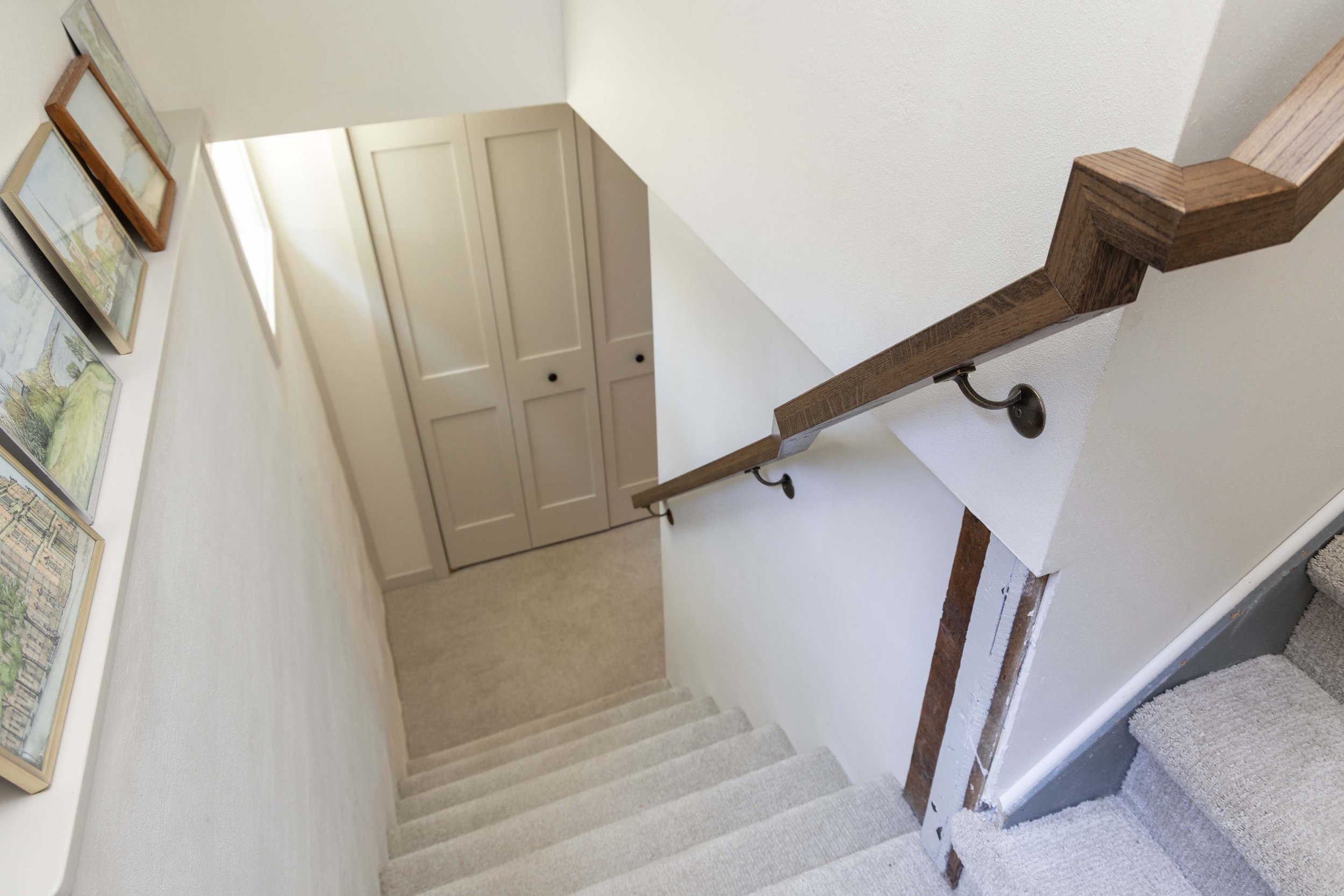 Carpeted basement staircase view looking down toward a custom painted storage closet door.