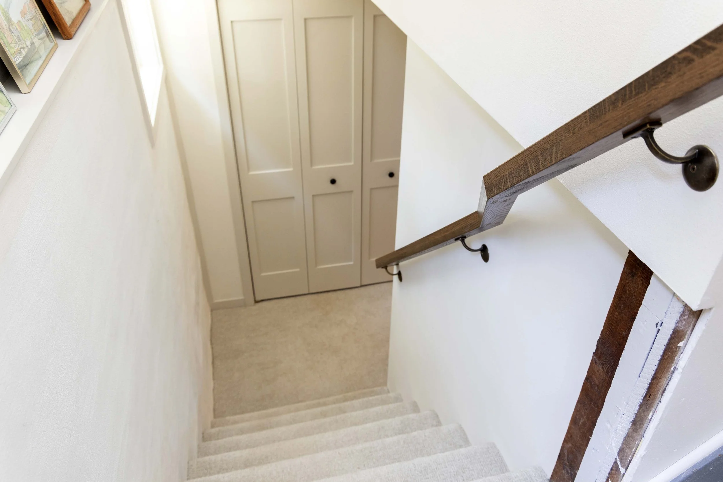 Straight-on view down a basement stairwell featuring a modern angular wood handrail.
