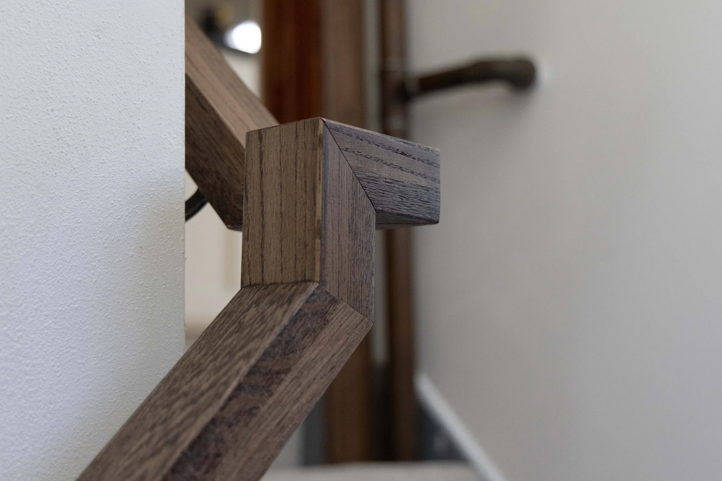 Close-up detail of a custom crafted geometric wood handrail on a basement staircase.