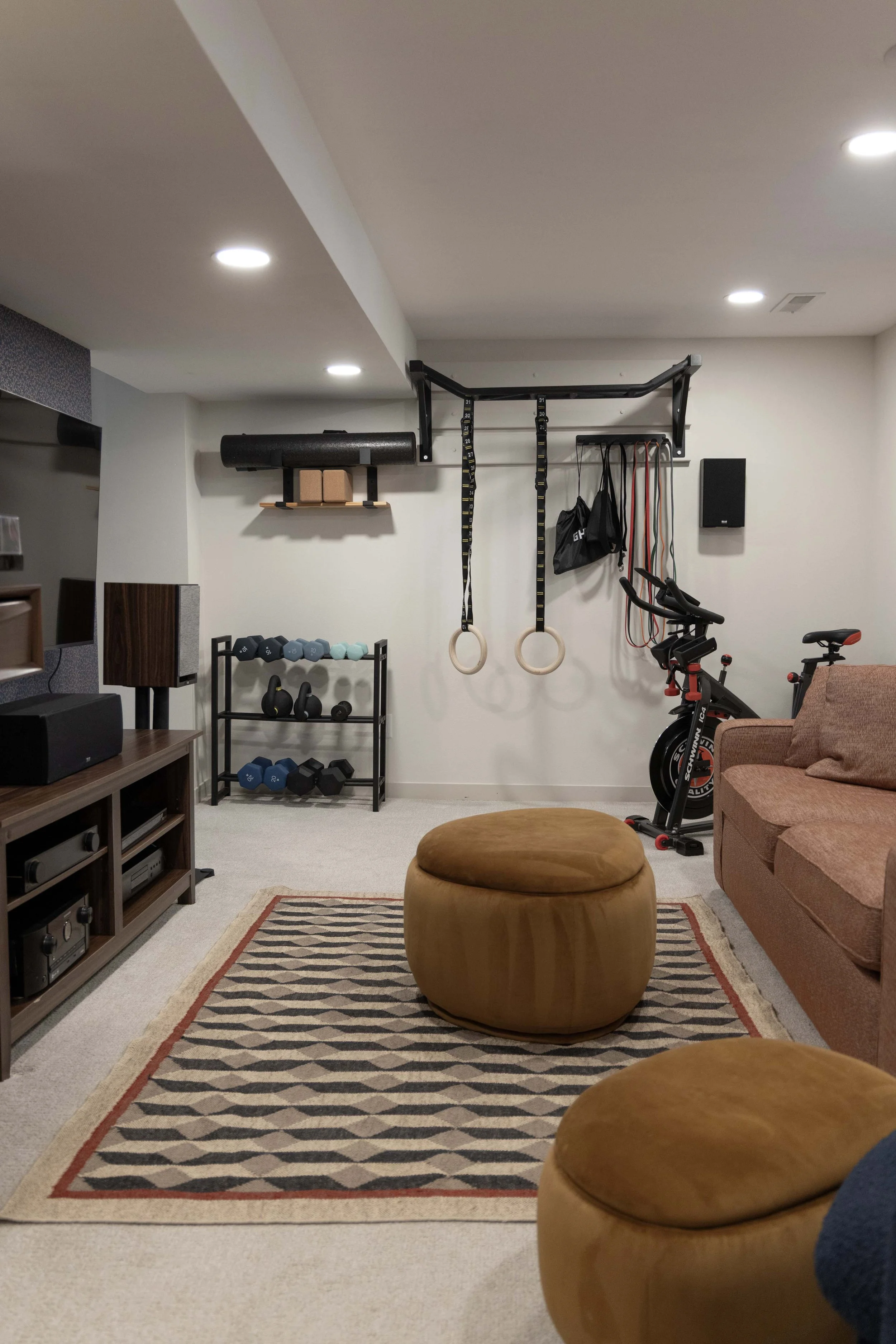 Basement family room remodel by Root Down Remodeling showcasing a TV media center and workout equipment area.