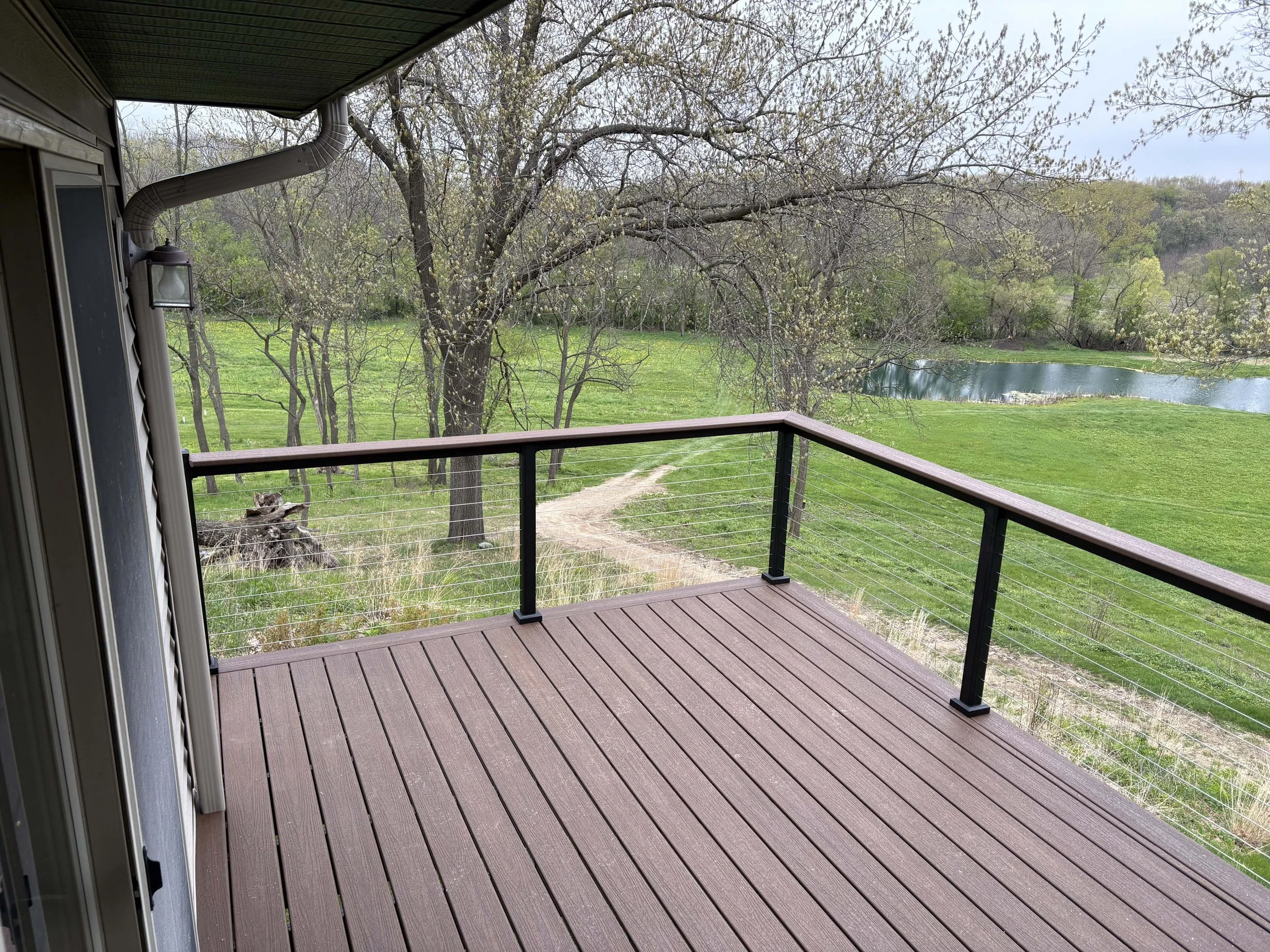 View from a custom backyard deck overlooking a scenic pond with a matching composite top railing.
