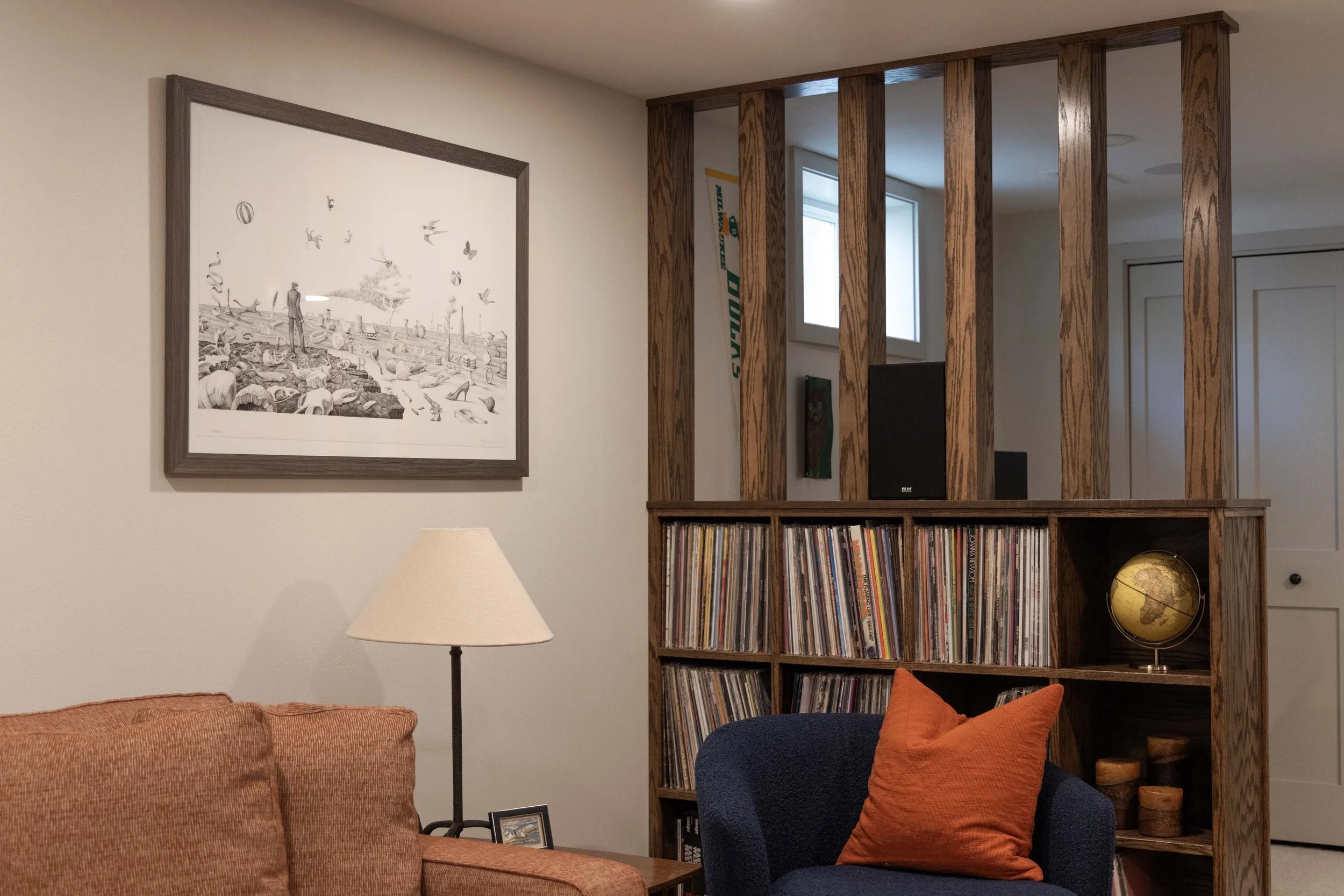 Custom wood mid-century style shelving unit holding a vinyl record collection in a basement.