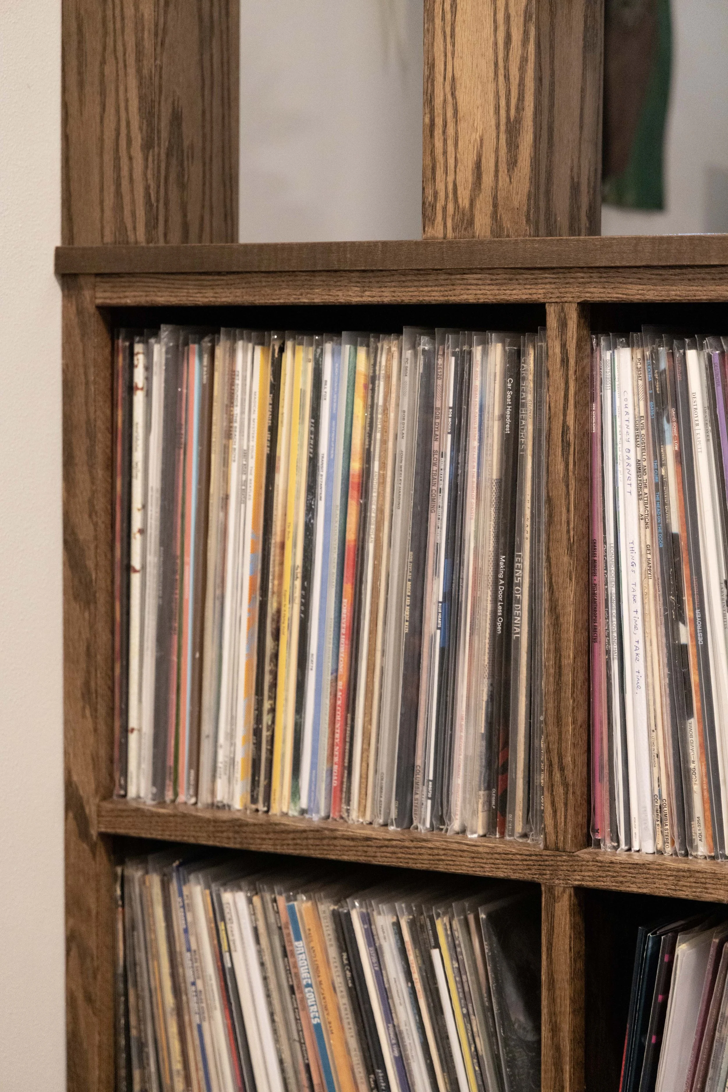 Detail shot of a custom oak shelving unit neatly packed with colorful vinyl record jackets.