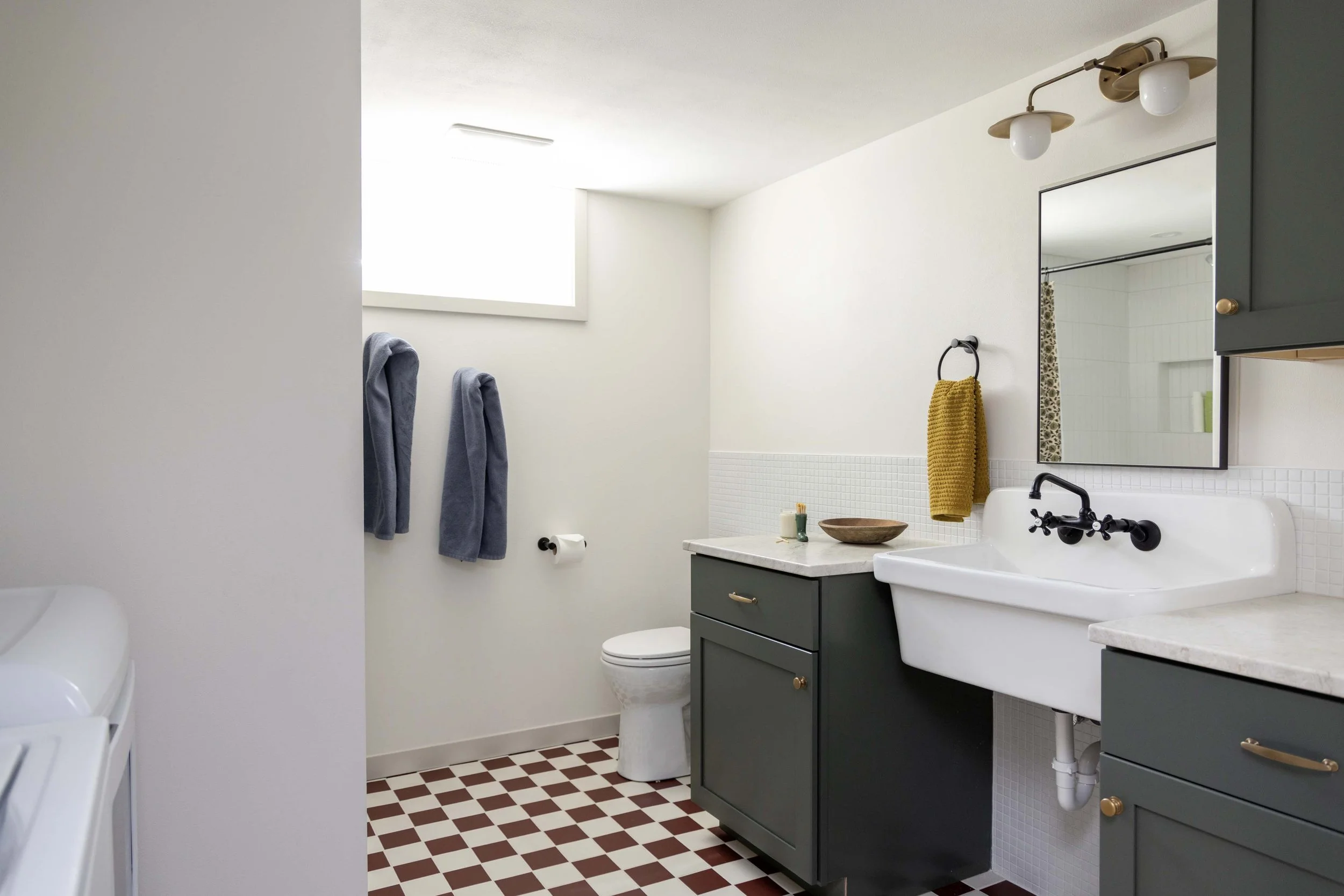 Full basement bathroom remodel showcasing a checkered floor, green vanity, and utility sink.