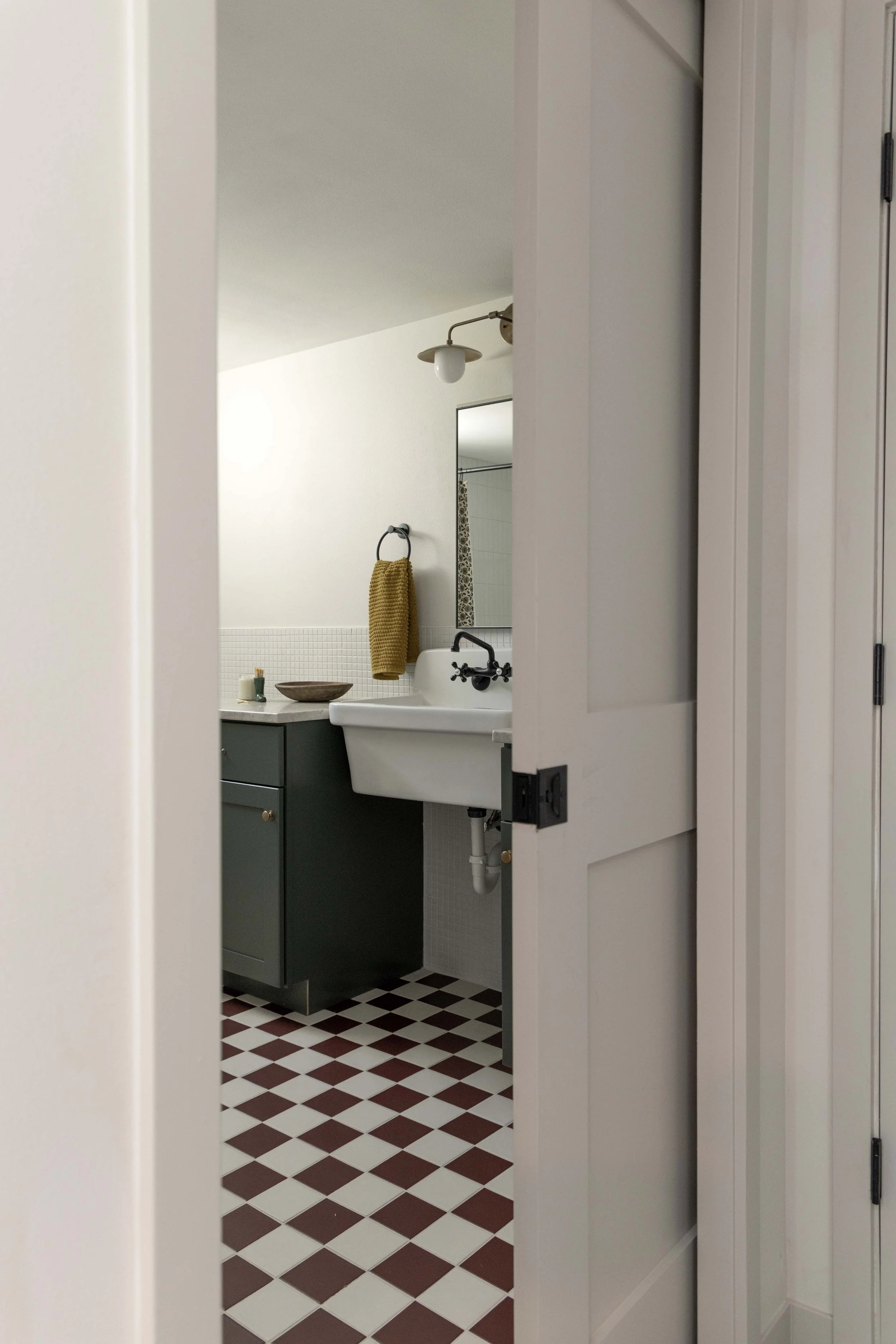 View through an open bathroom doorway highlighting a unique checkerboard tile floor pattern.