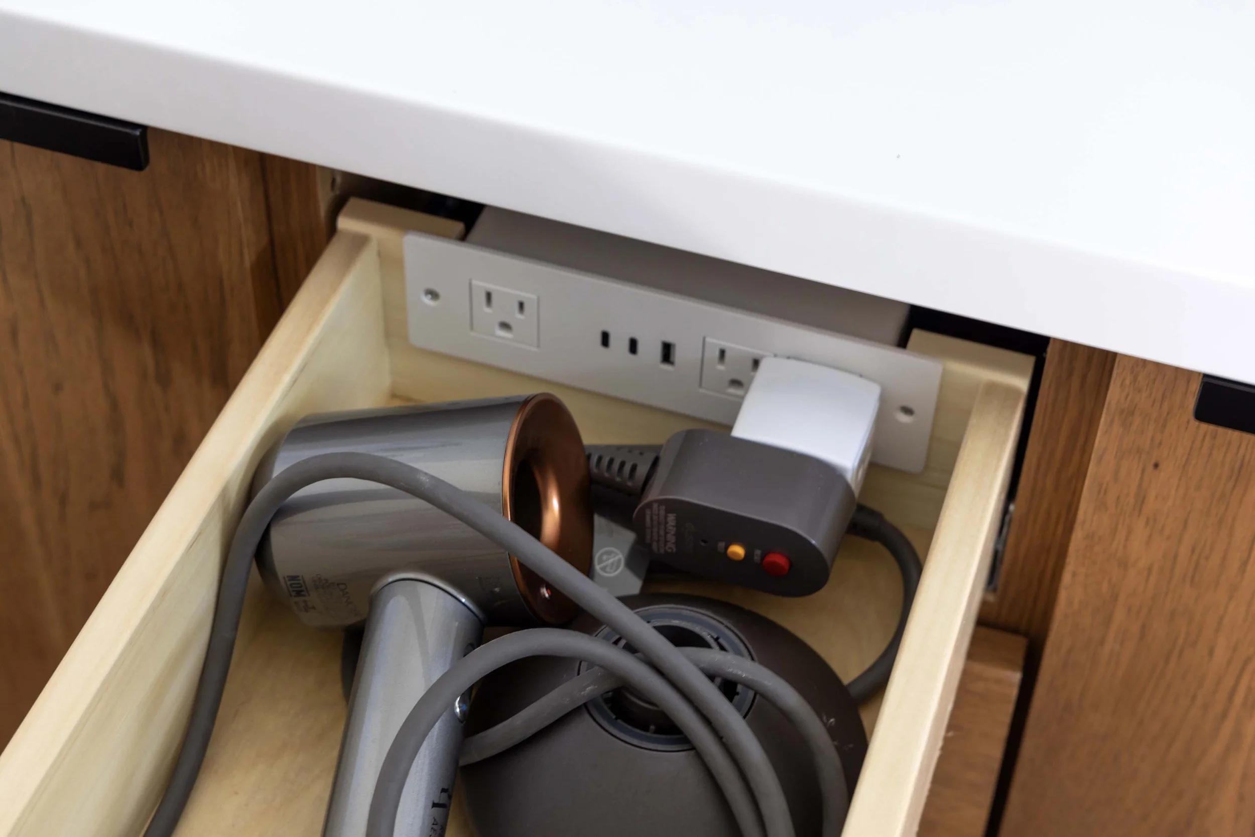 Custom vanity drawer organizer built by Root Down Remodeling featuring an integrated power outlet strip for hair dryers.