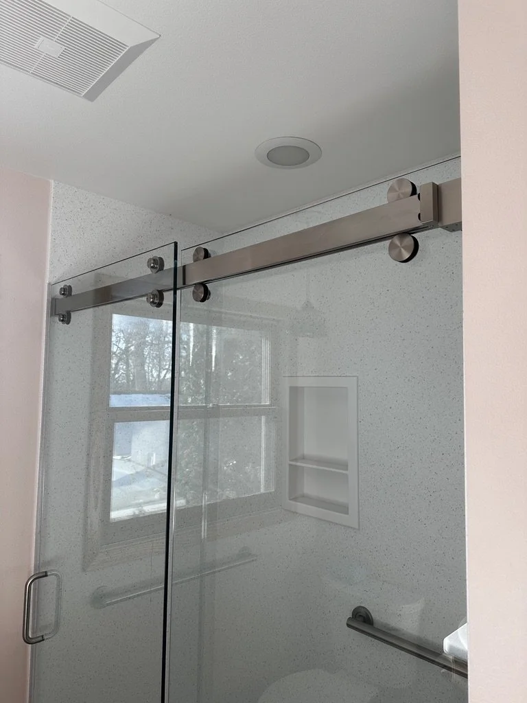 Frameless glass sliding shower door installation over a custom solid surface base.