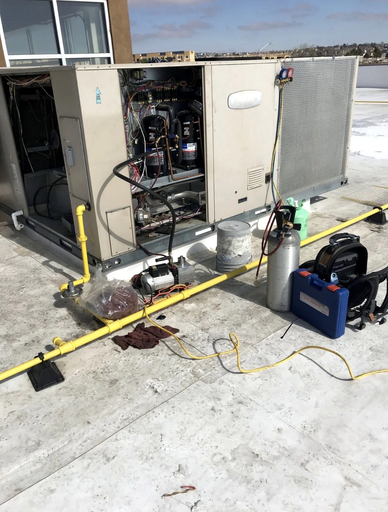 HVAC or refrigeration unit on a rooftop with tools, pipes, and equipment nearby.