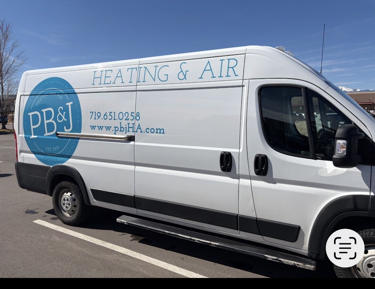 White service van with blue logo and text for heating and air conditioning company, PBJ, parked in a lot during daytime.