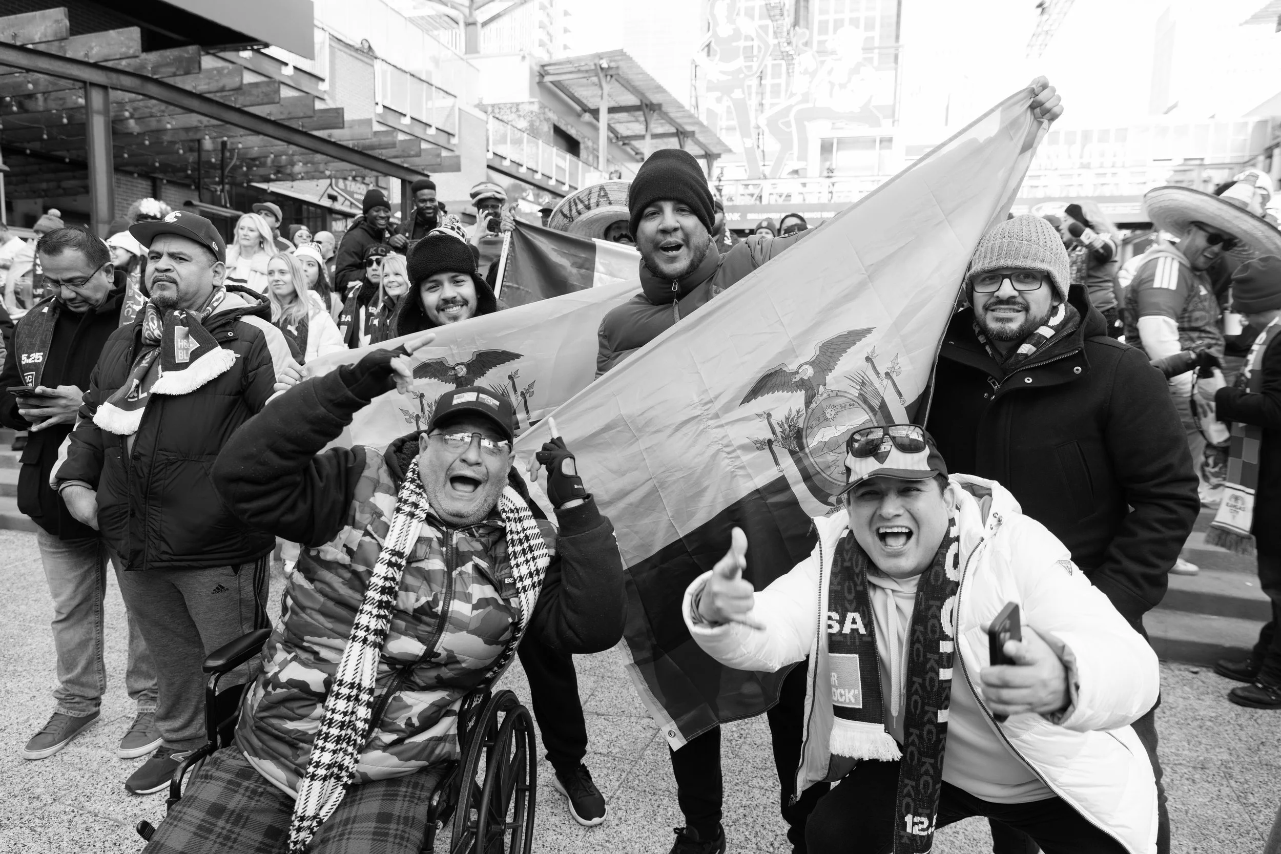 Group of diverse people celebrating outdoors, holding a Utah state flag, showing excitement and joy.