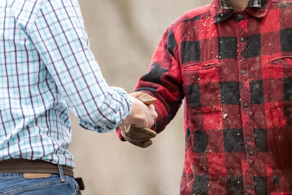 Two men shaking hands in cold weather one with gloves