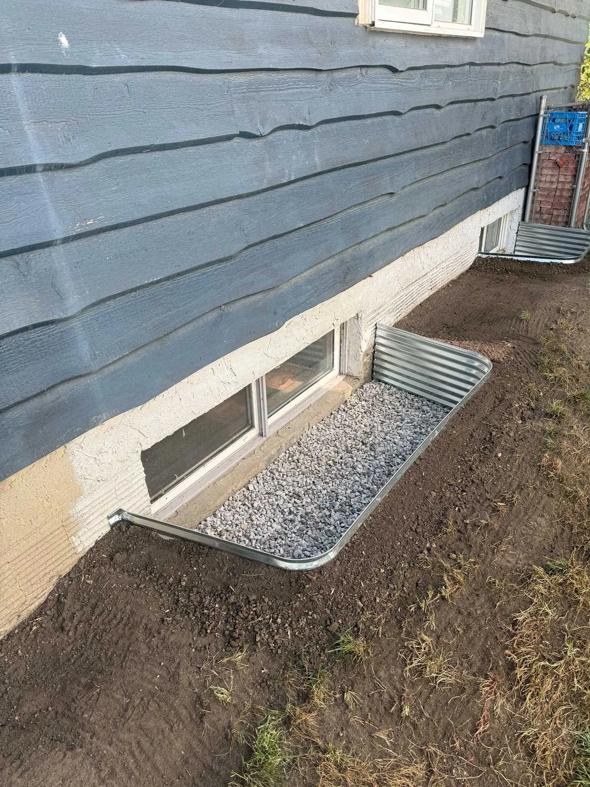 Completed window well with gravel drainage allowing natural light into the basement.