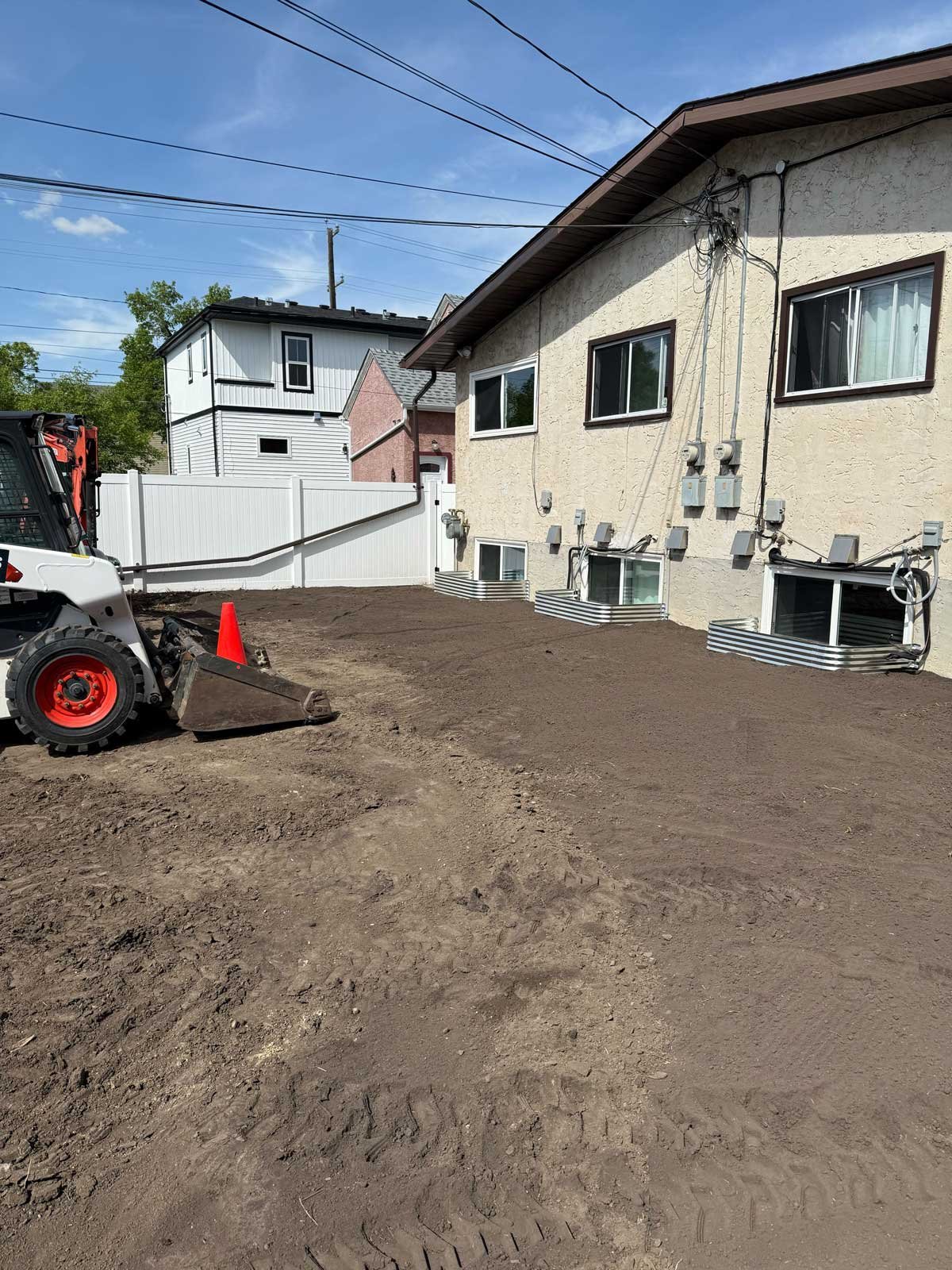 Fresh grading being completed around a home to slope soil away from the foundation for proper drainage.
